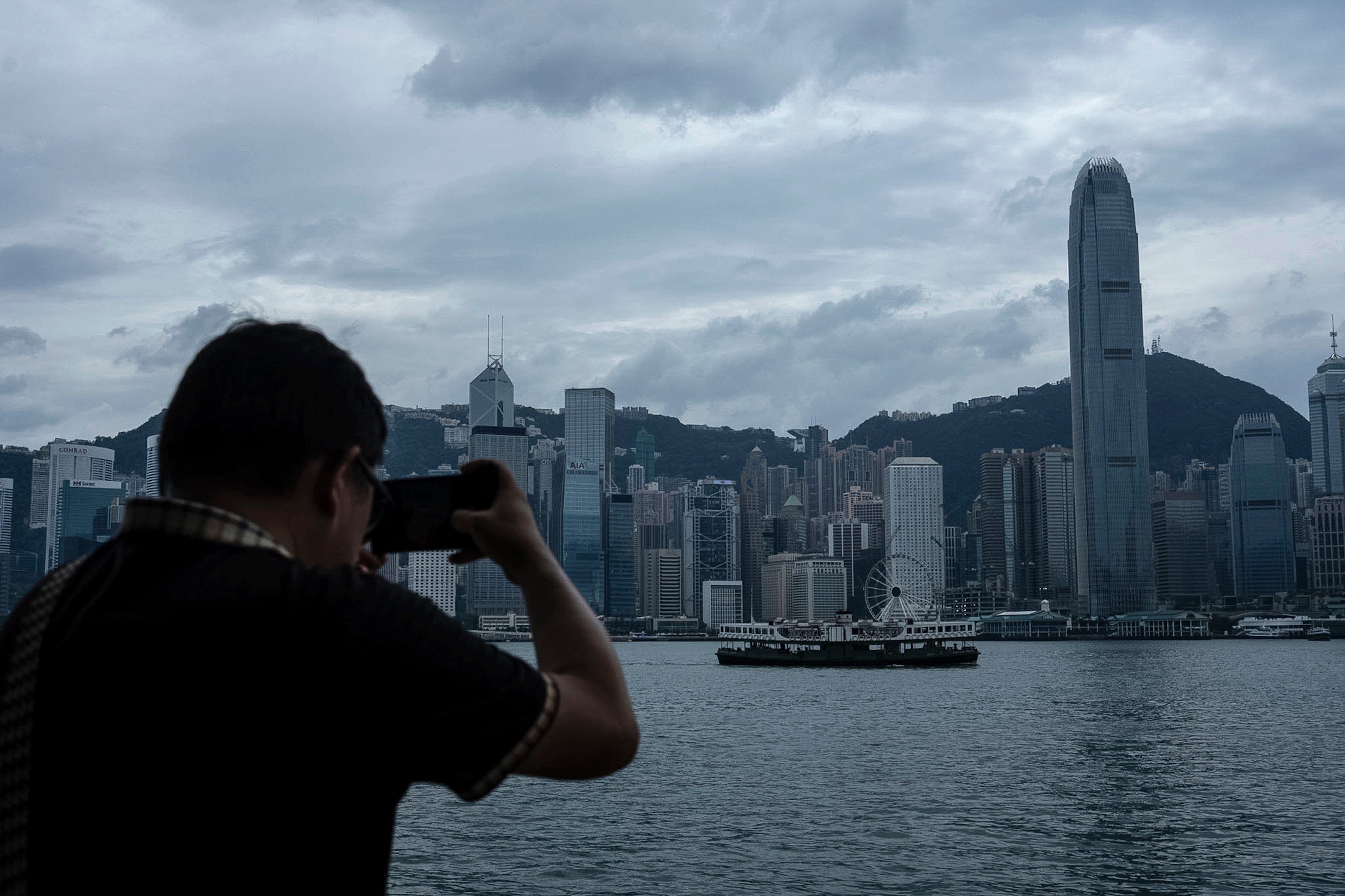 A pedestrian takes pictures at the Victoria Harbor waterfront ahead of the arrival of Ragasa in Hong Kong