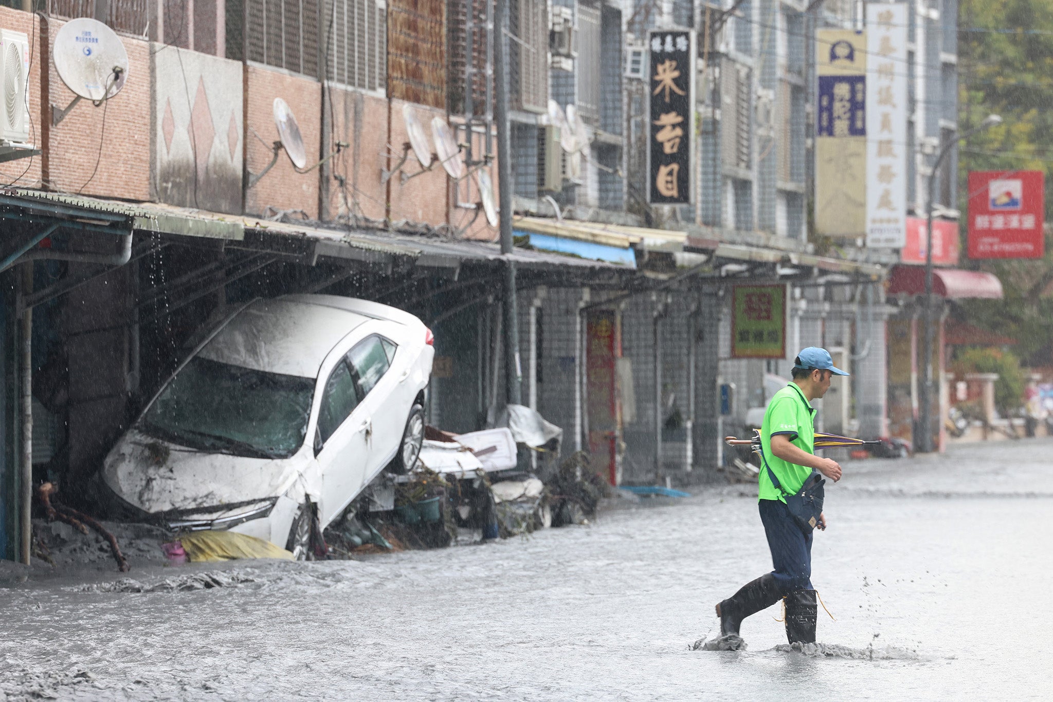 A man walks past a damaged car, swept away by floodwaters, in Hualien