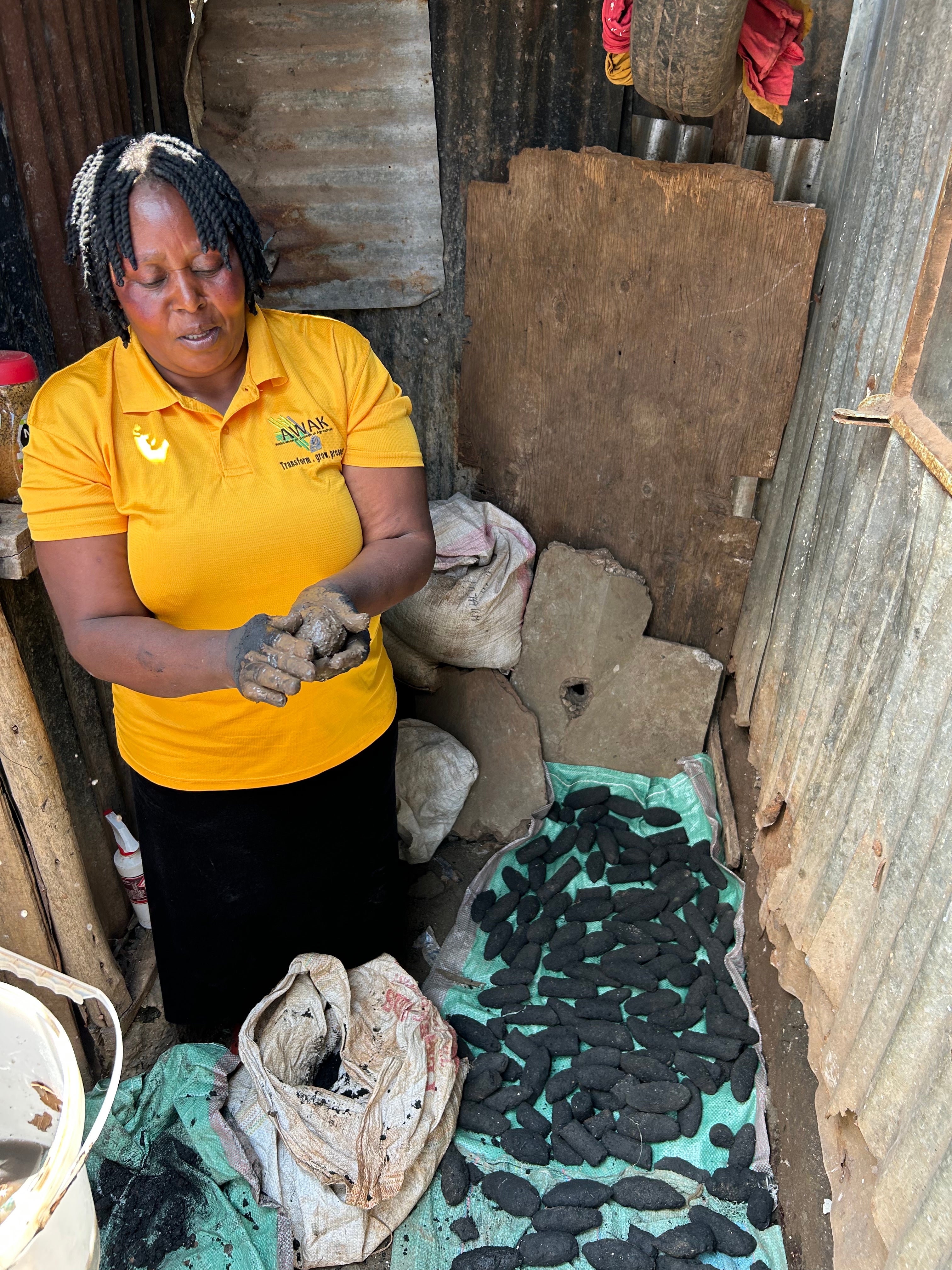 Consolata proudly demonstrates how she manufactures the charcoal briquettes that she sells