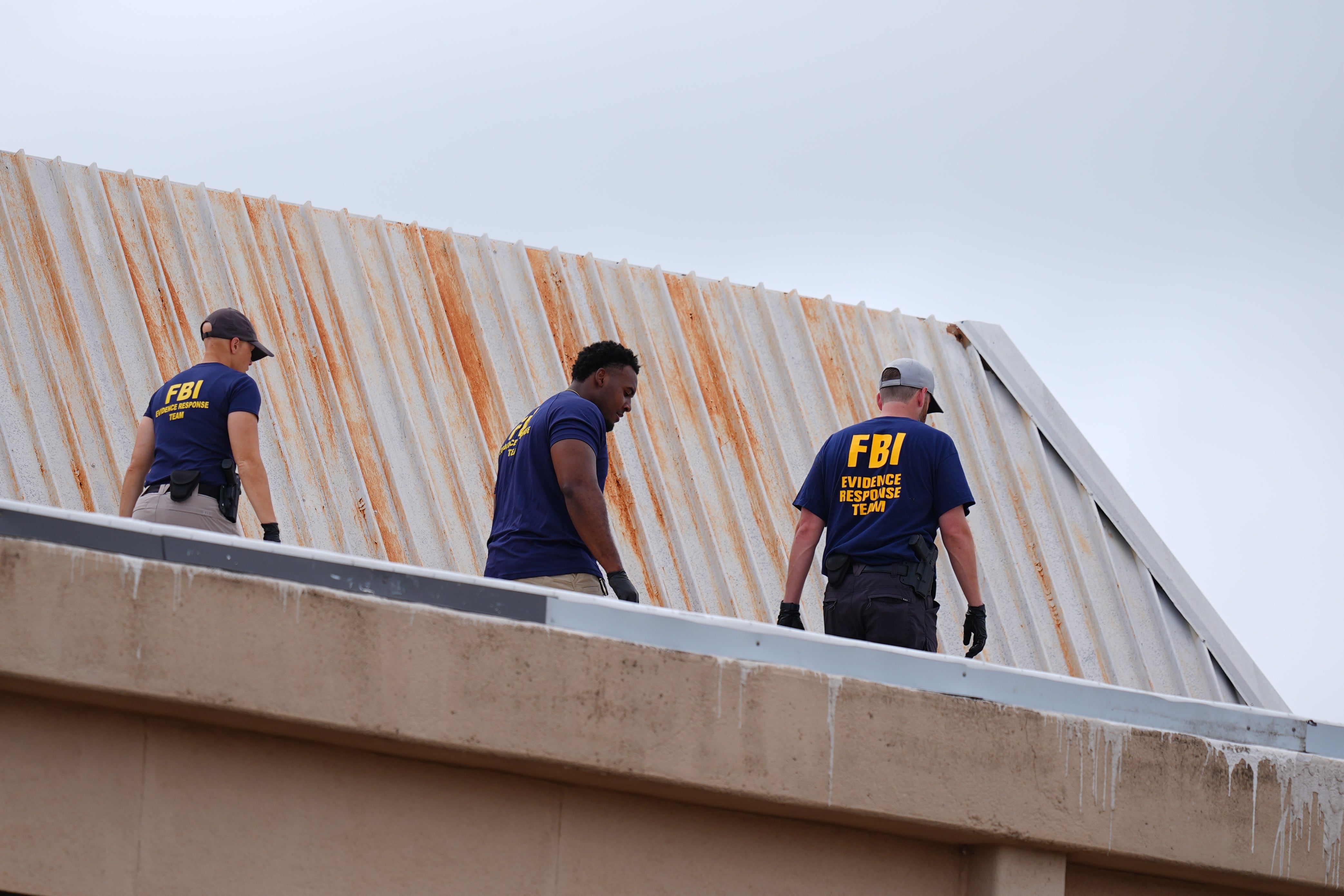FBI agents inspect the roof of an apartment building near the scene of the shooting