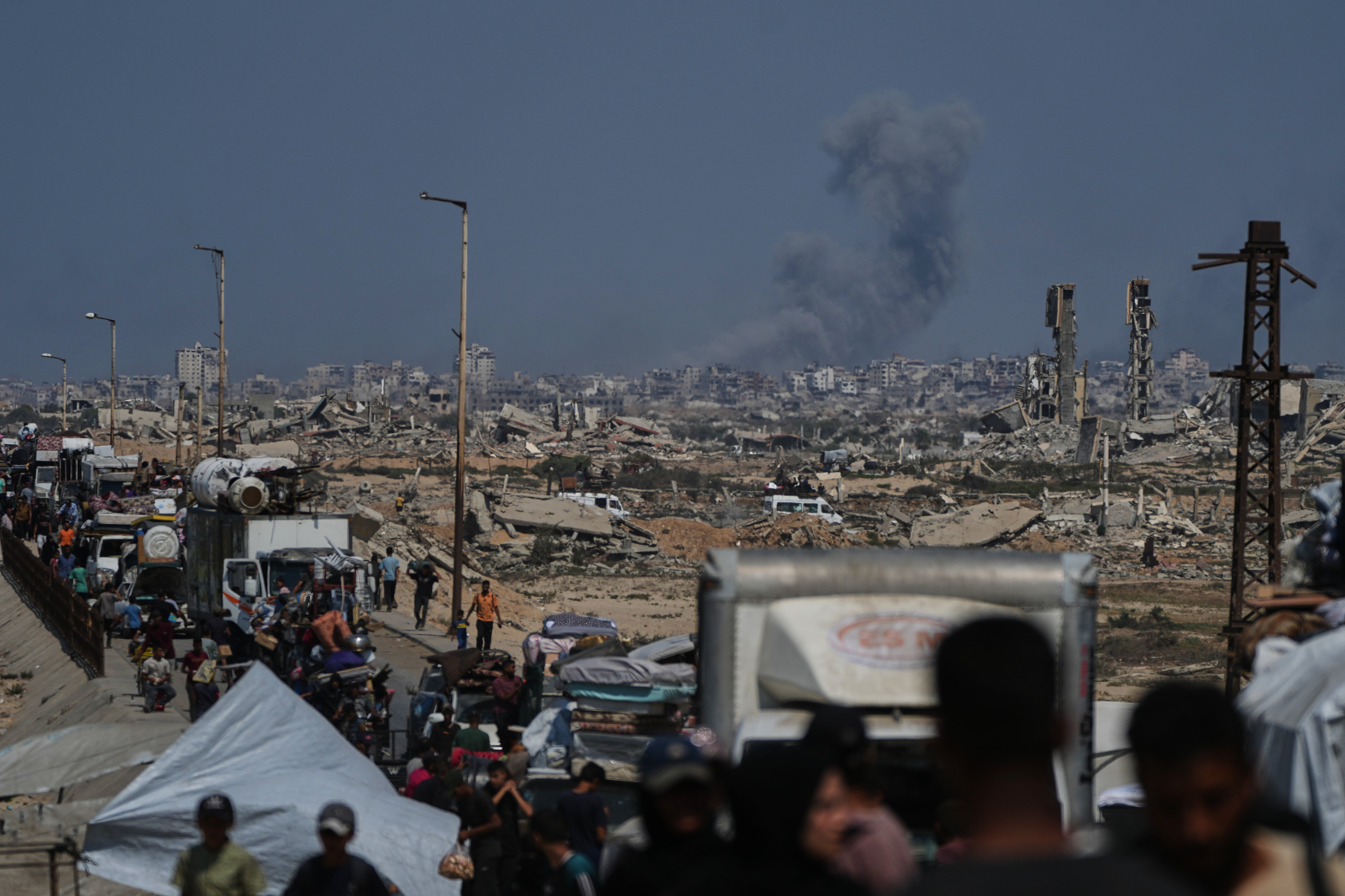 Smoke billows over Gaza City following an Israeli airstrike, as displaced Palestinians flee northern Gaza through Wadi Gaza