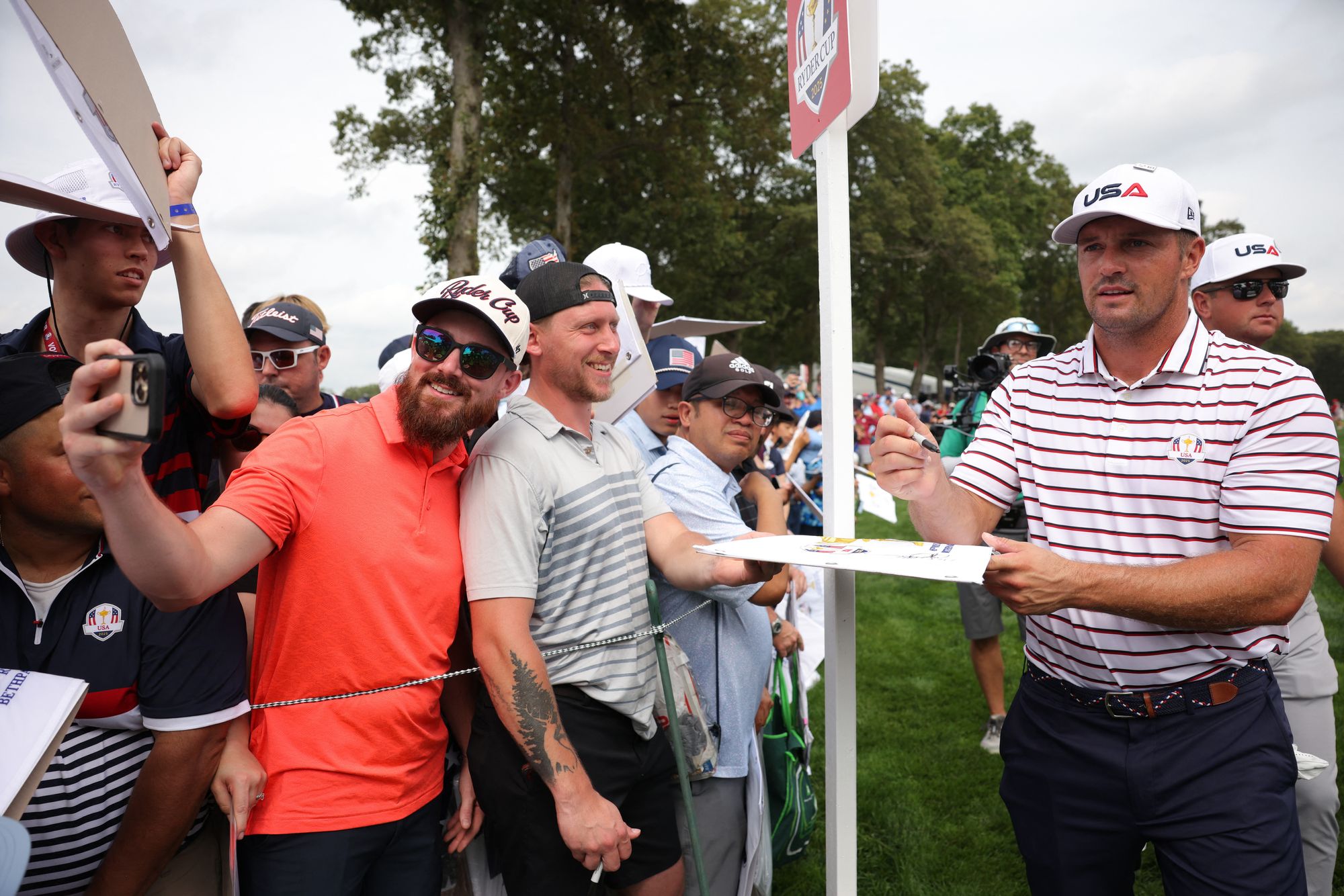 Bryson DeChambeau signs autographs for fans during a practice round