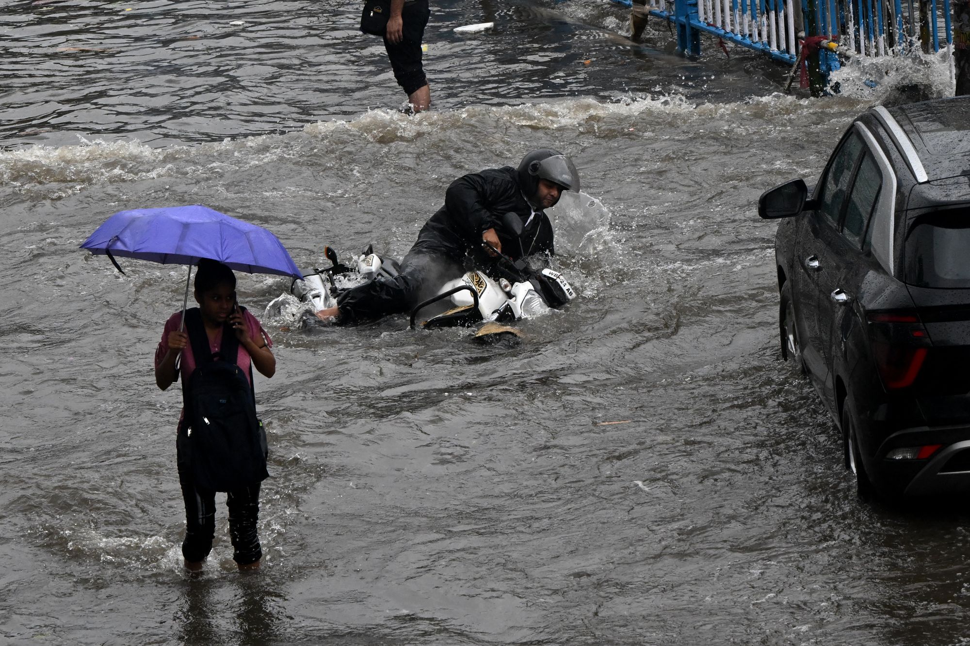 A motorist falls on a waterlogged road after heavy rain in Kolkata on 23 September 2025