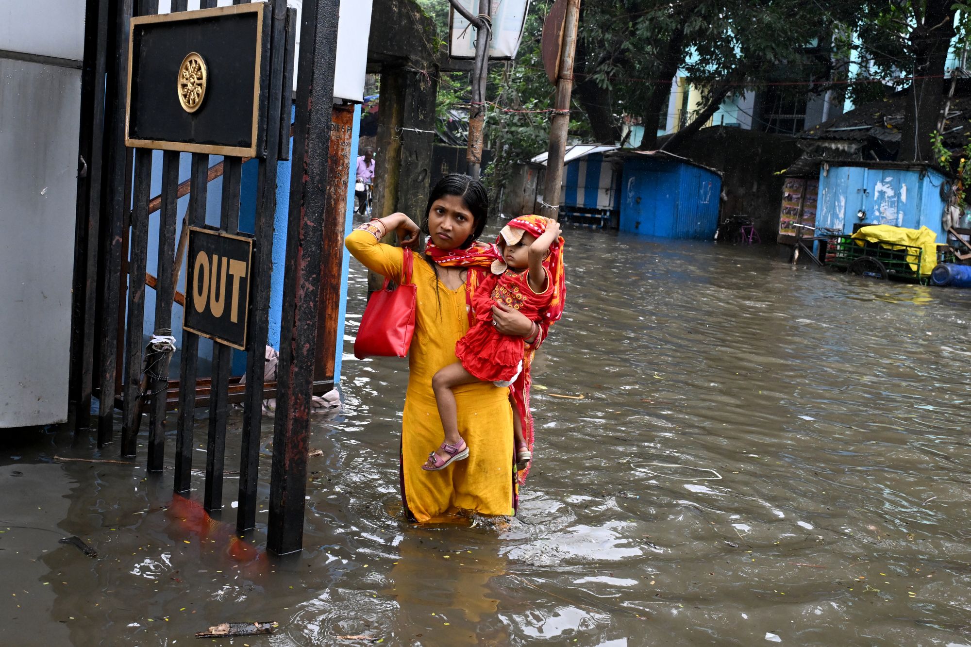 A woman holds a child as she wades through a waterlogged street in Kolkata on 23 September 2025