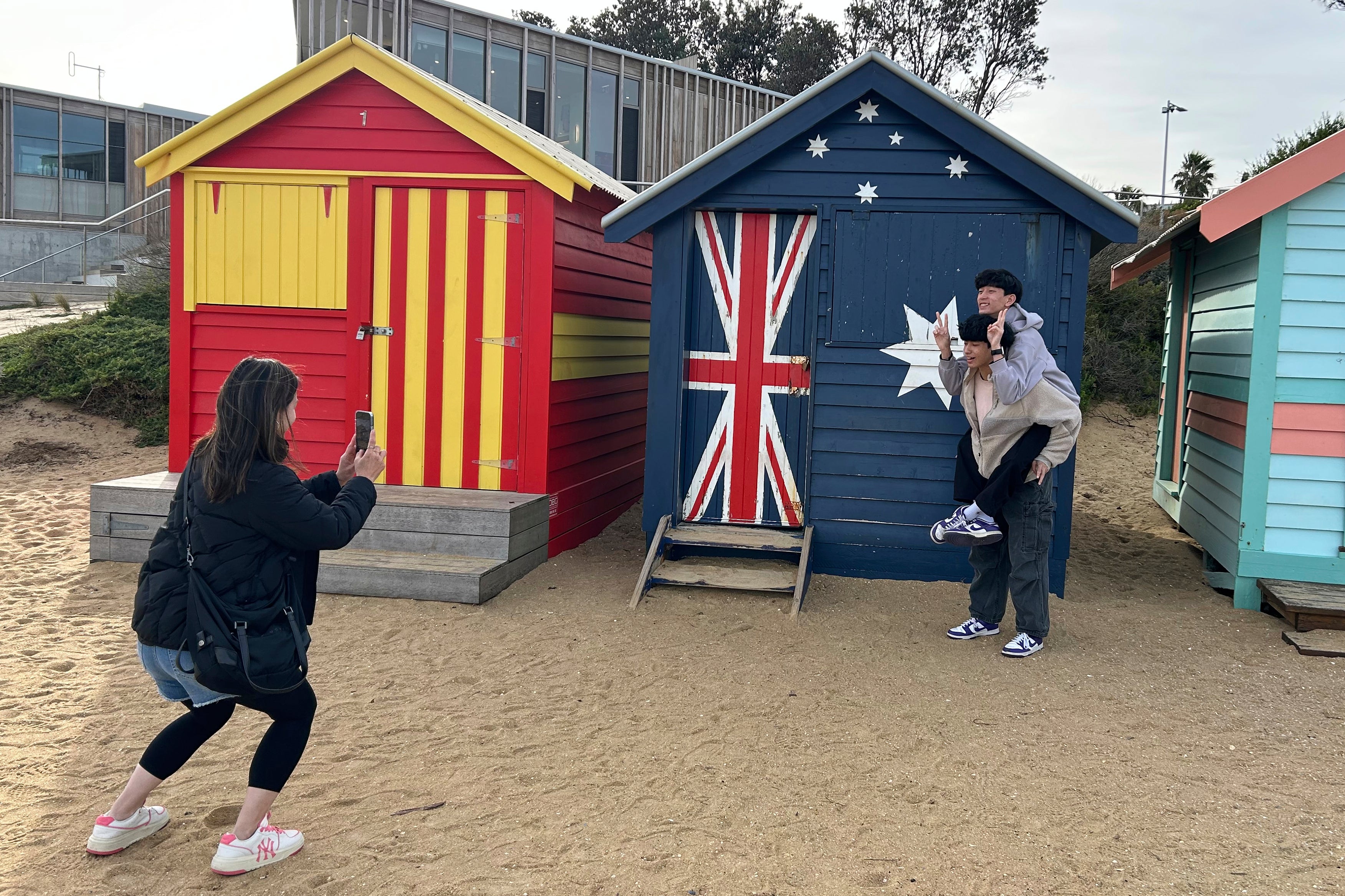 Visitors take photos by the Bathing boxes at Brighton Beach in Melbourne