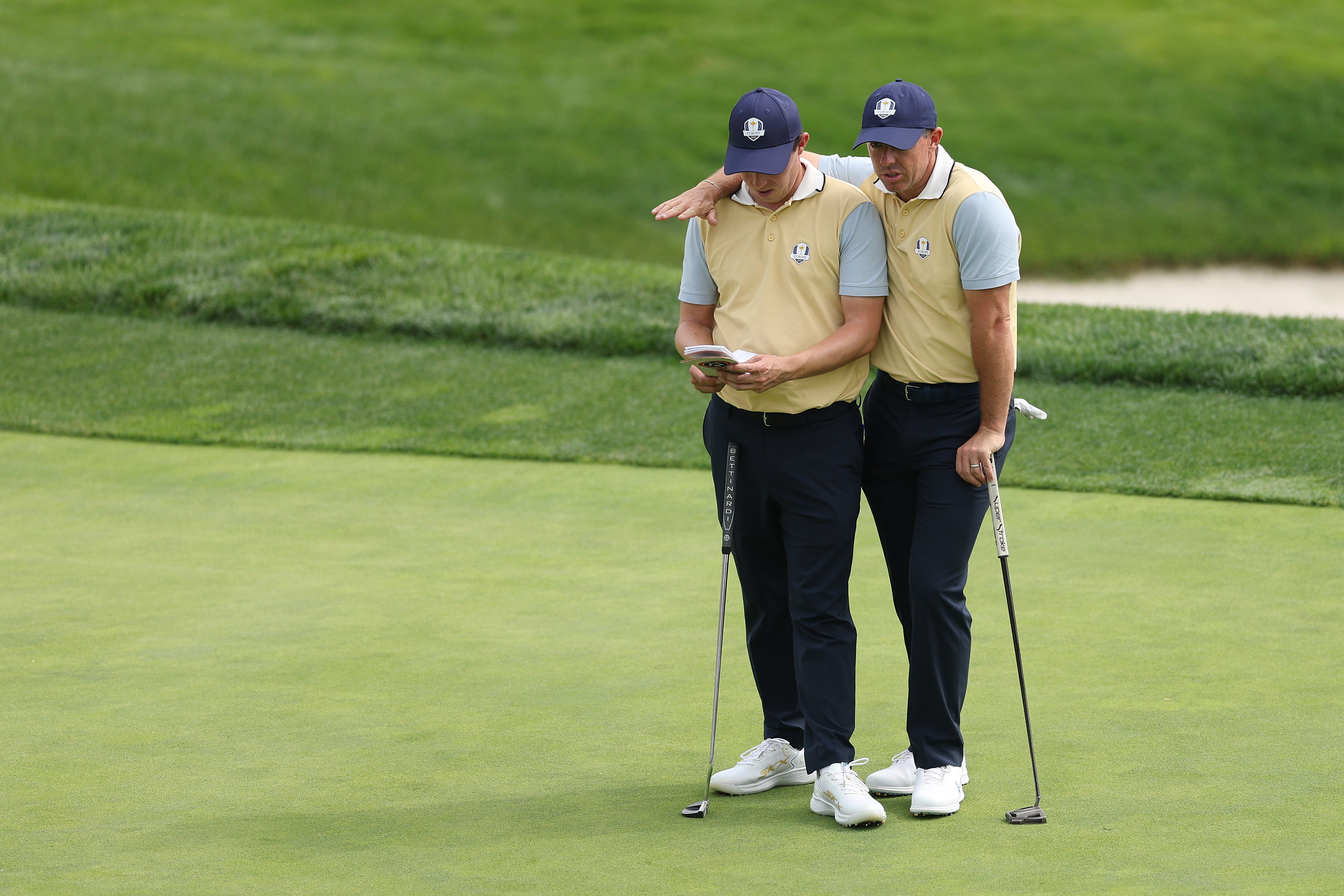 Matt Fitzpatrick and Rory McIlroy of Team Europe look at a yardage book during a practice round