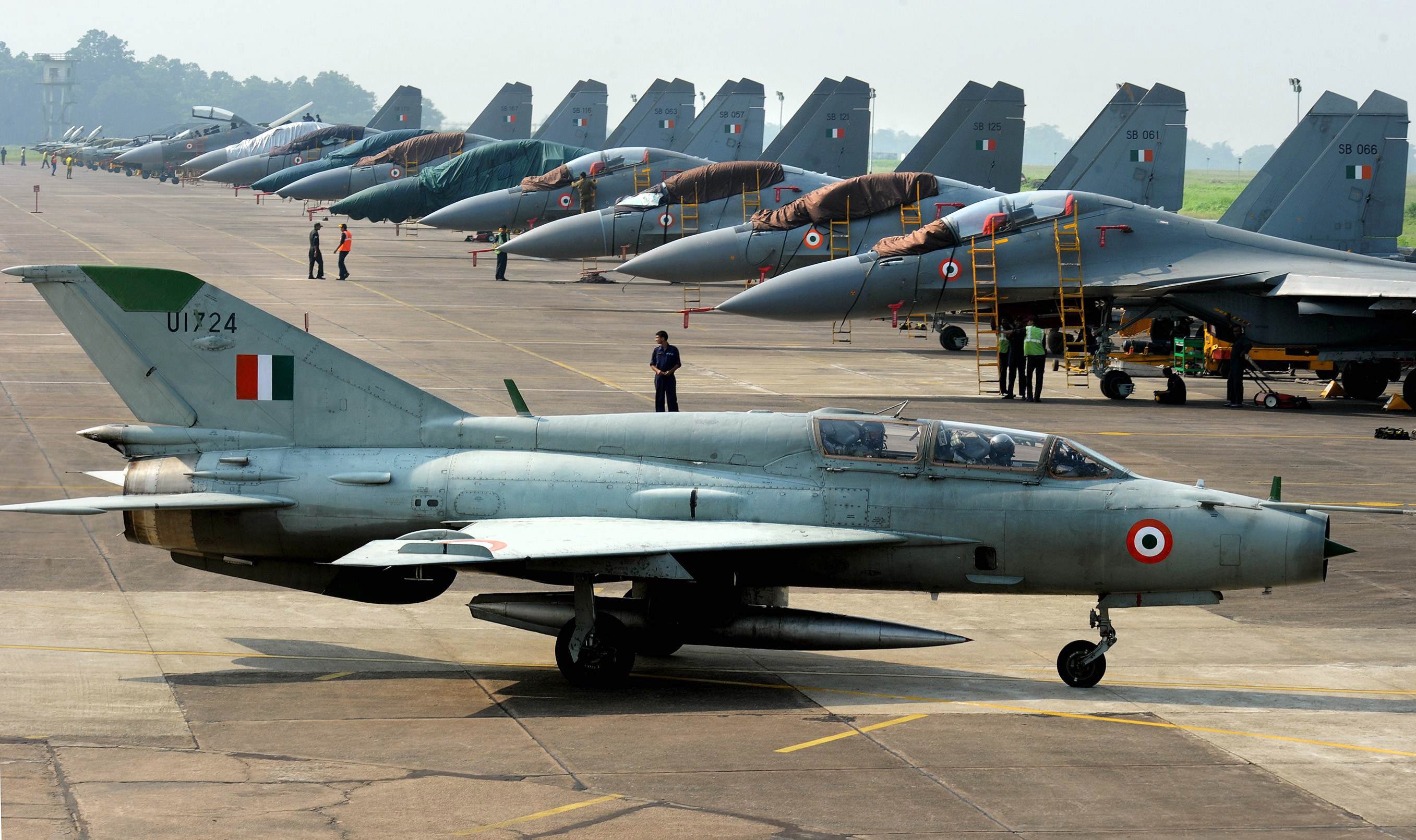 A MiG-21 passes near Sukhoi-30 fighter jets before a drill for Air Force Day celebrations in 2011