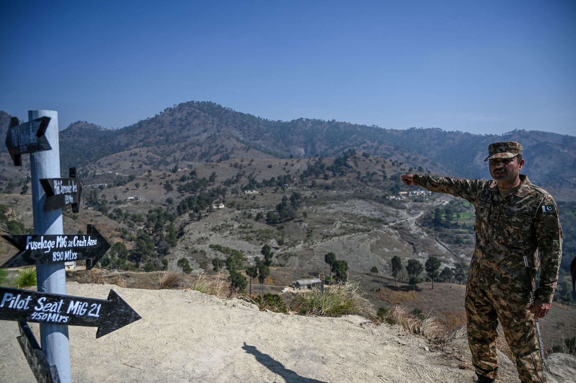 A Pakistani soldier points to the site at Horran village where an Indian MiG-21 fighter aircraft was shot down and its pilot, Wing Commander Abhinandan Varthaman, captured in 2019
