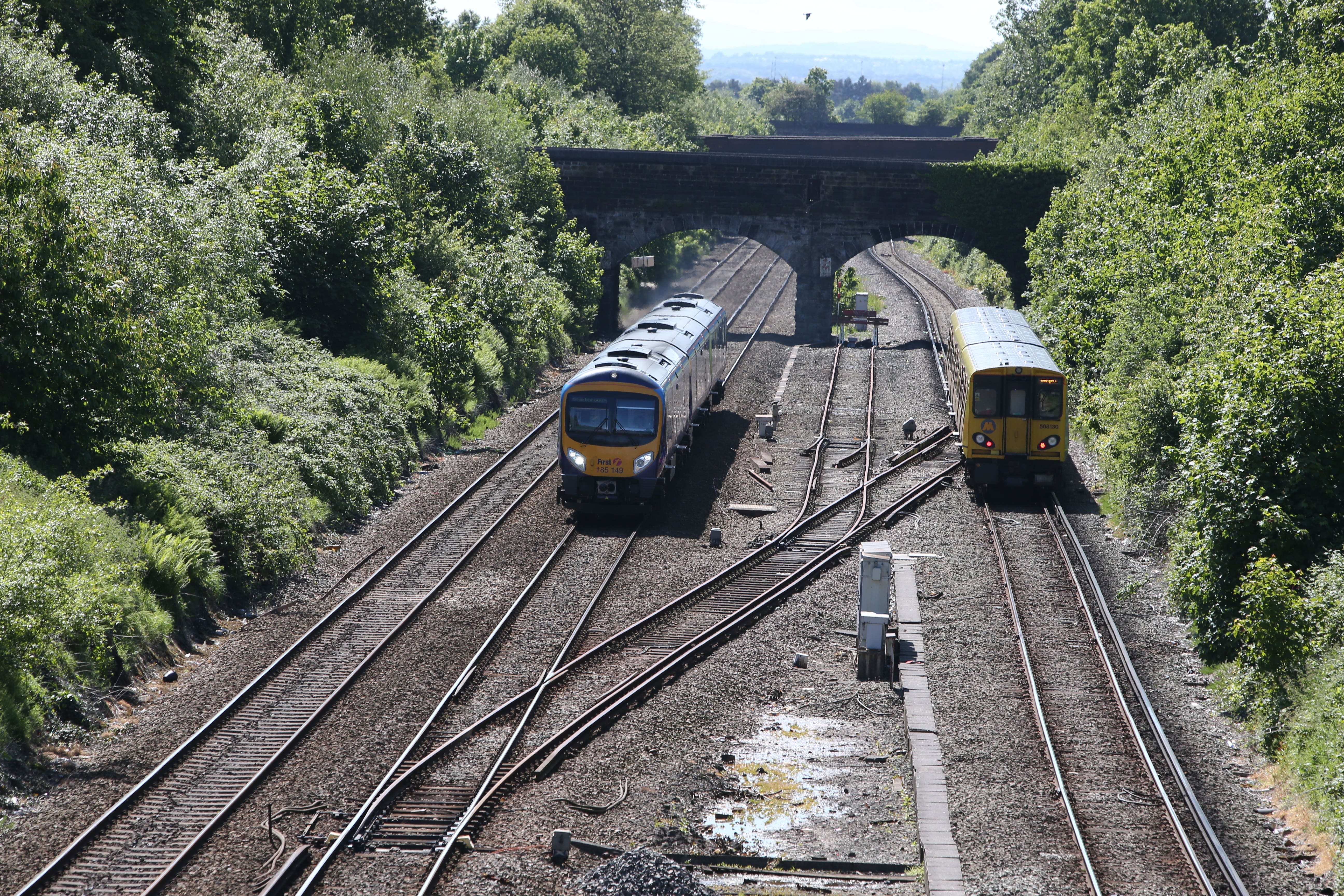 A Merseyrail train (right) travel and a First Transpennine Express pass along track at Hunt’s Cross station (PA)