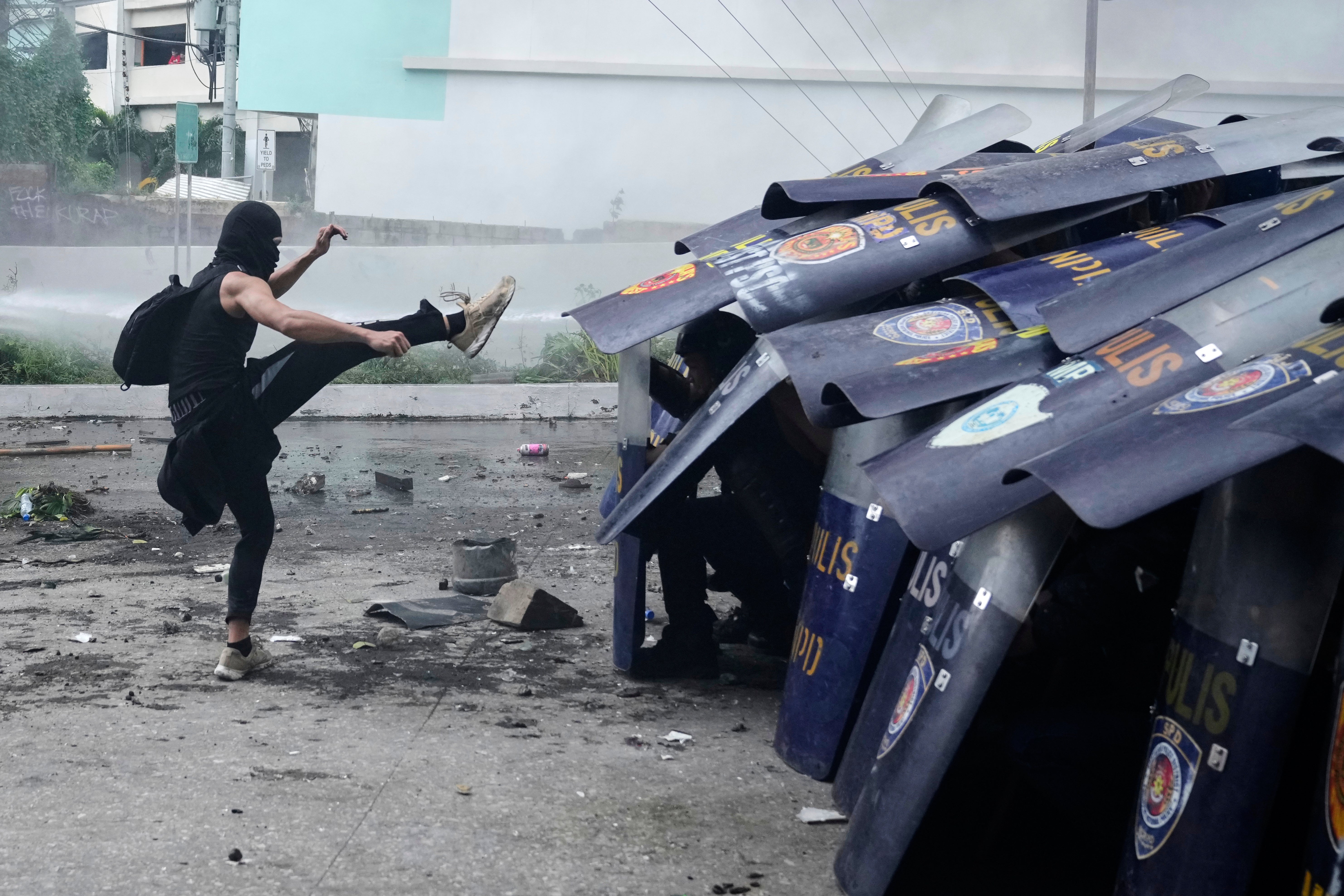 An anti-corruption protester kicks the shield of a policeman during clashes in Manila, Philippines, on 21 September 2025