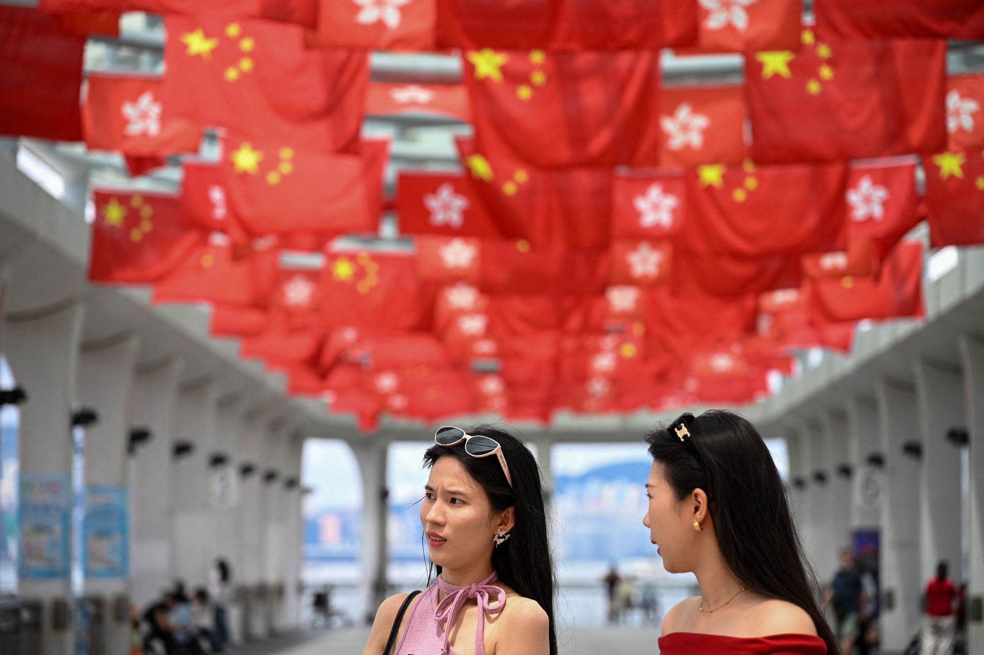 Tourists walk under Hong Kong and China flags