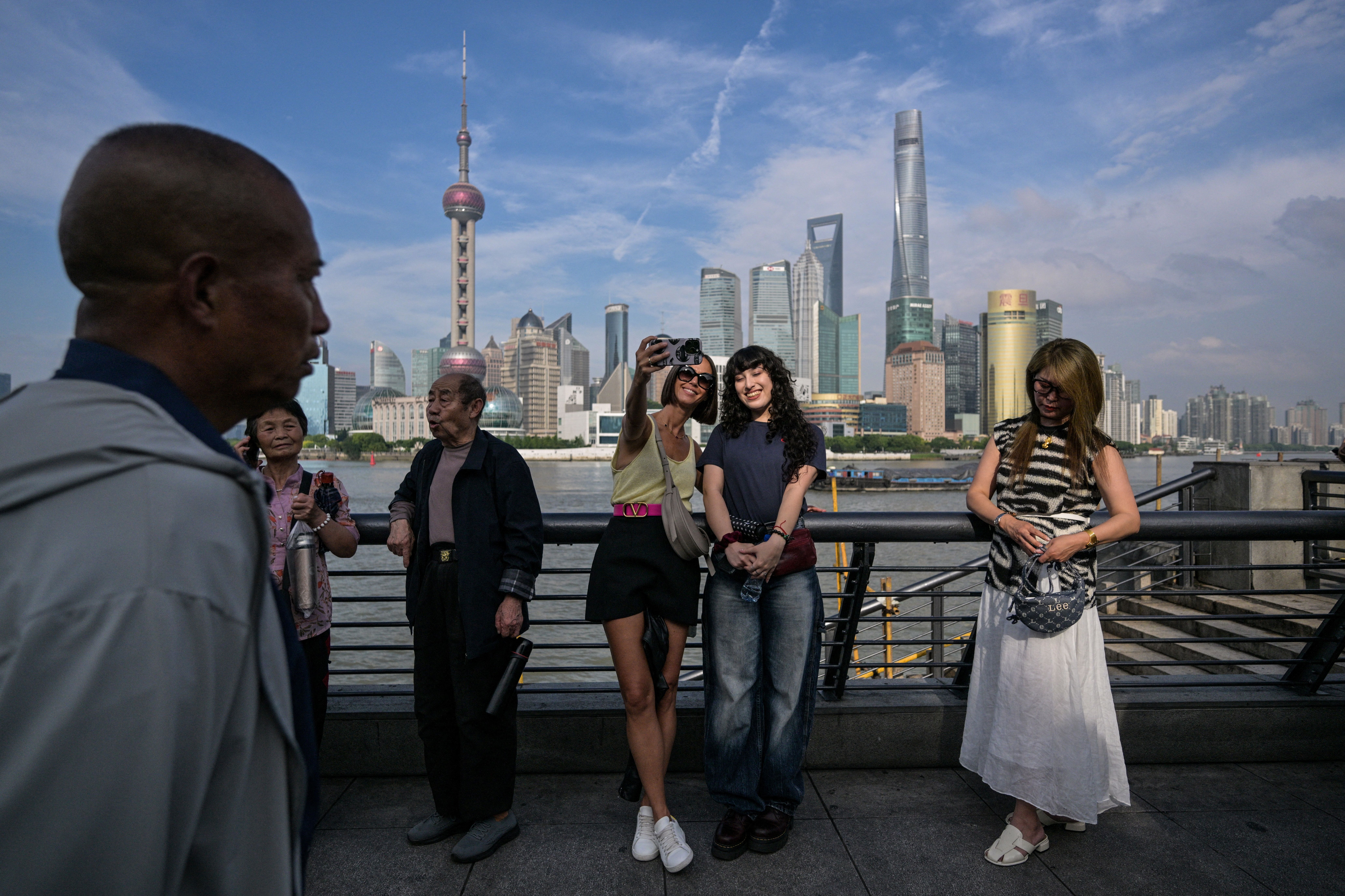 Tourists take a selfie on the Bund promenade along the Huangpu river in Shanghai