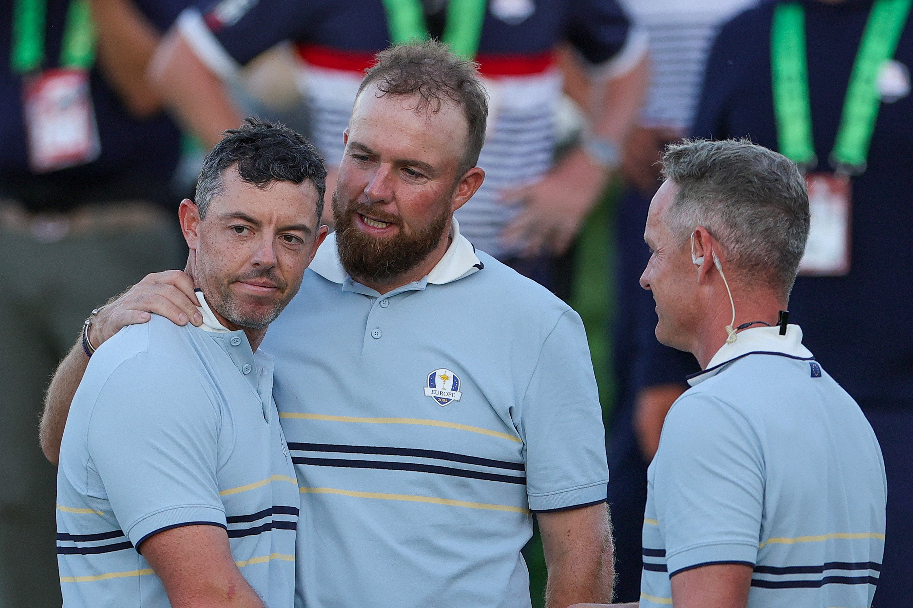 Shane Lowry of Team Europe hugs teammate Rory McIlroy as they talk to Captain Luke Donald of Team Europe