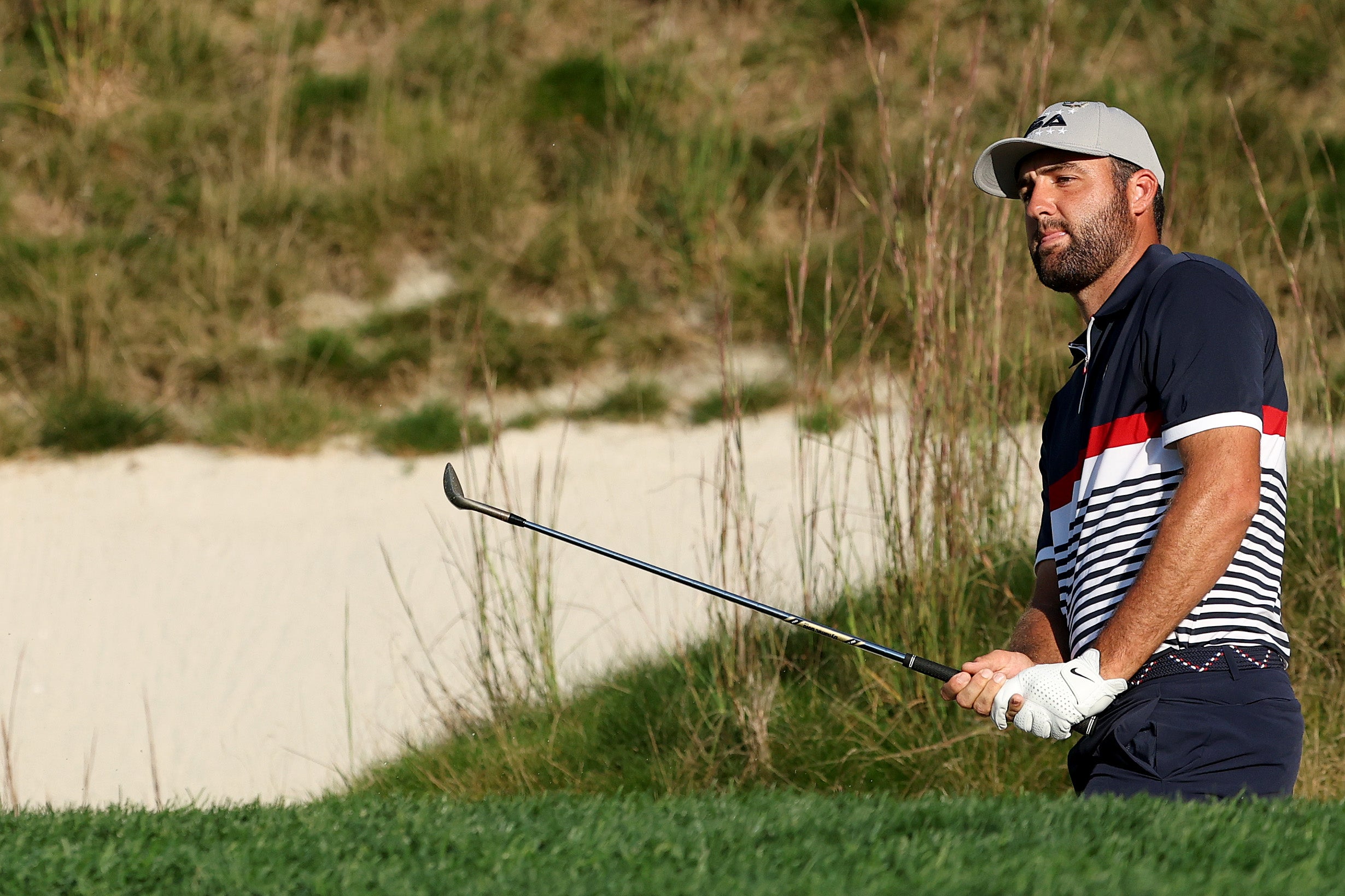Scottie Scheffler of Team United States watches a greenside bunker shot on the 14th hole