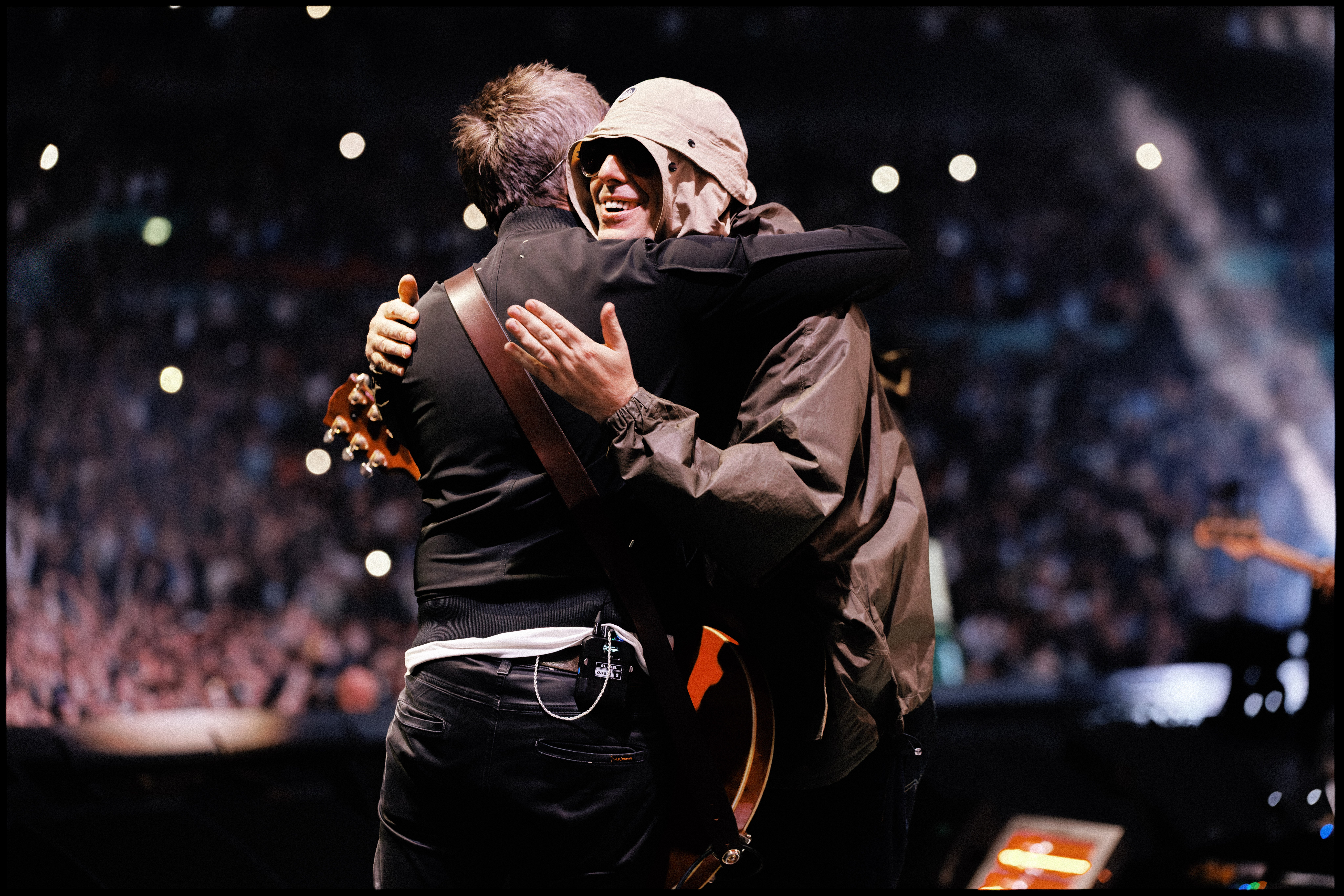 <p>Liam and Noel Gallagher hug during a Wembley Stadium show for the Oasis reunion tour</p>
