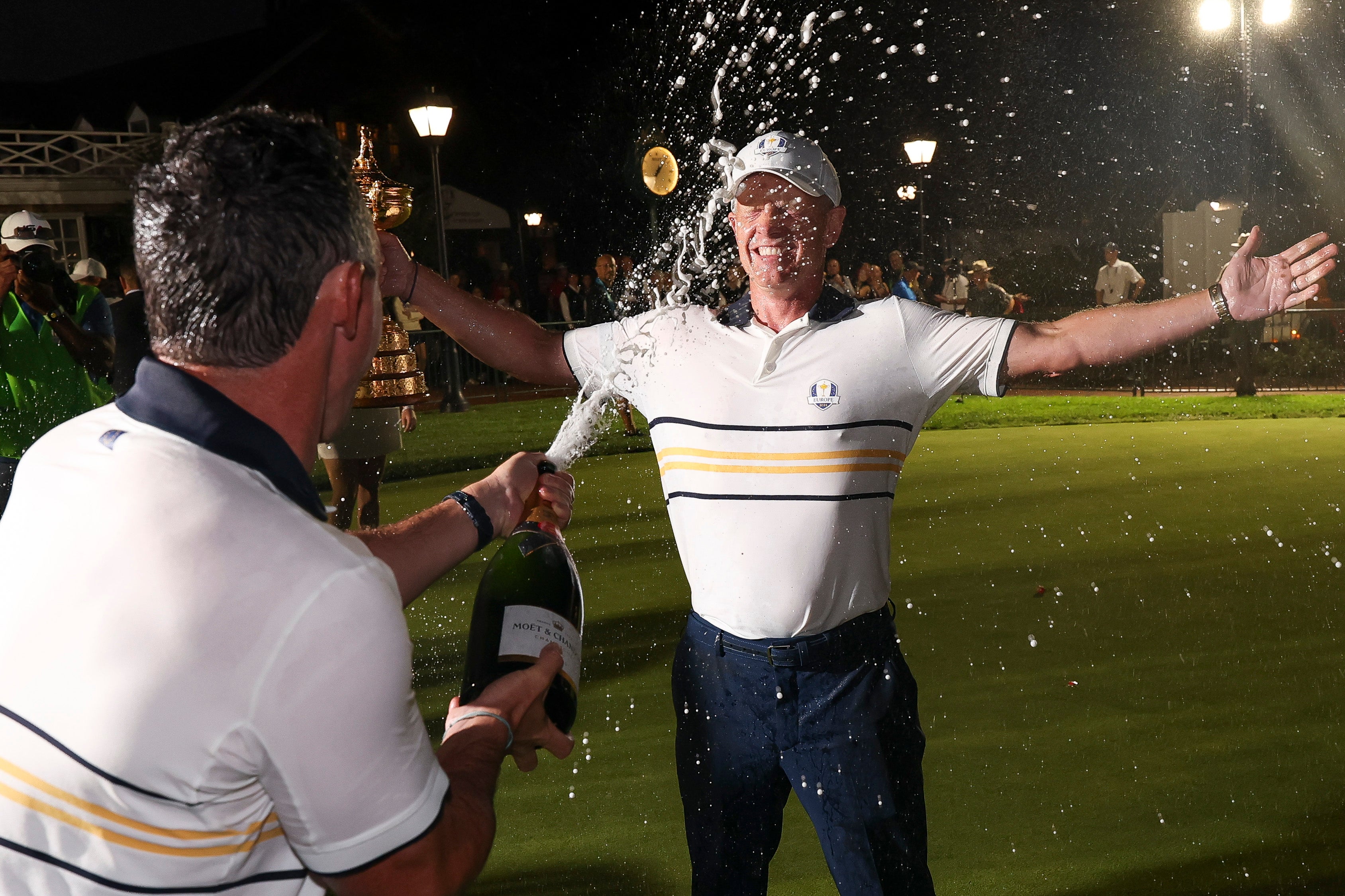 Captain Luke Donald (R) of Team Europe holds the Ryder Cup trophy as he is doused with champagne by Rory McIlroy after Team Europe defeated Team United States 15-13 during the Sunday singles matches of the 2025 Ryder Cup at Black Course at Bethpage State Park Golf Course on September 28, 2025 in Farmingdale, New York. (Photo by Andrew Redington/Getty Images)