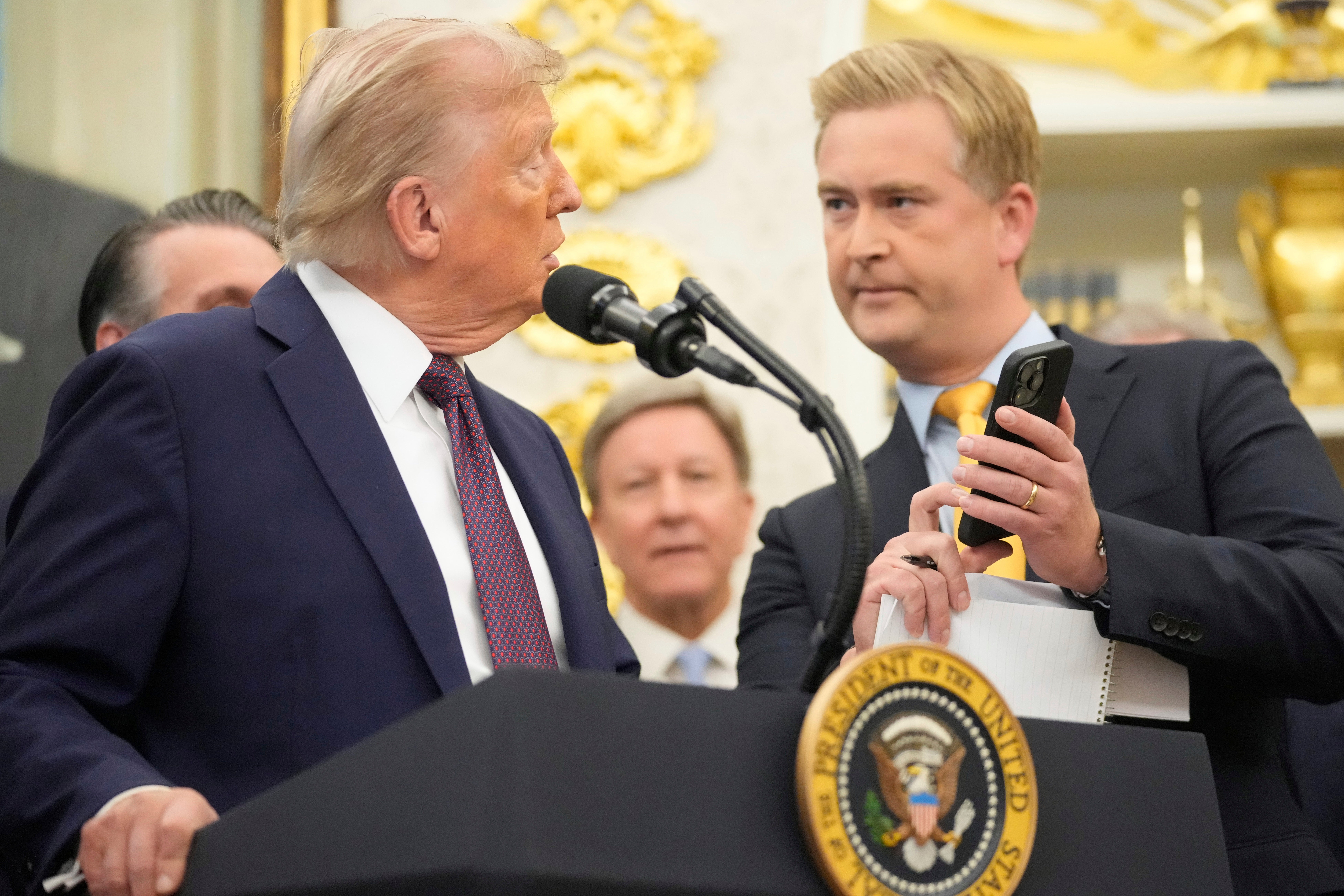 FOX News reporter Peter Doocy, right, shows President Donald Trump a photo on his phone during an event about the relocation of U.S. Space Command headquarters from Colorado to Alabama in the Oval Office of the White House, Sept. 2, 2025, in Washington. (AP Photo/Mark Schiefelbein, File)