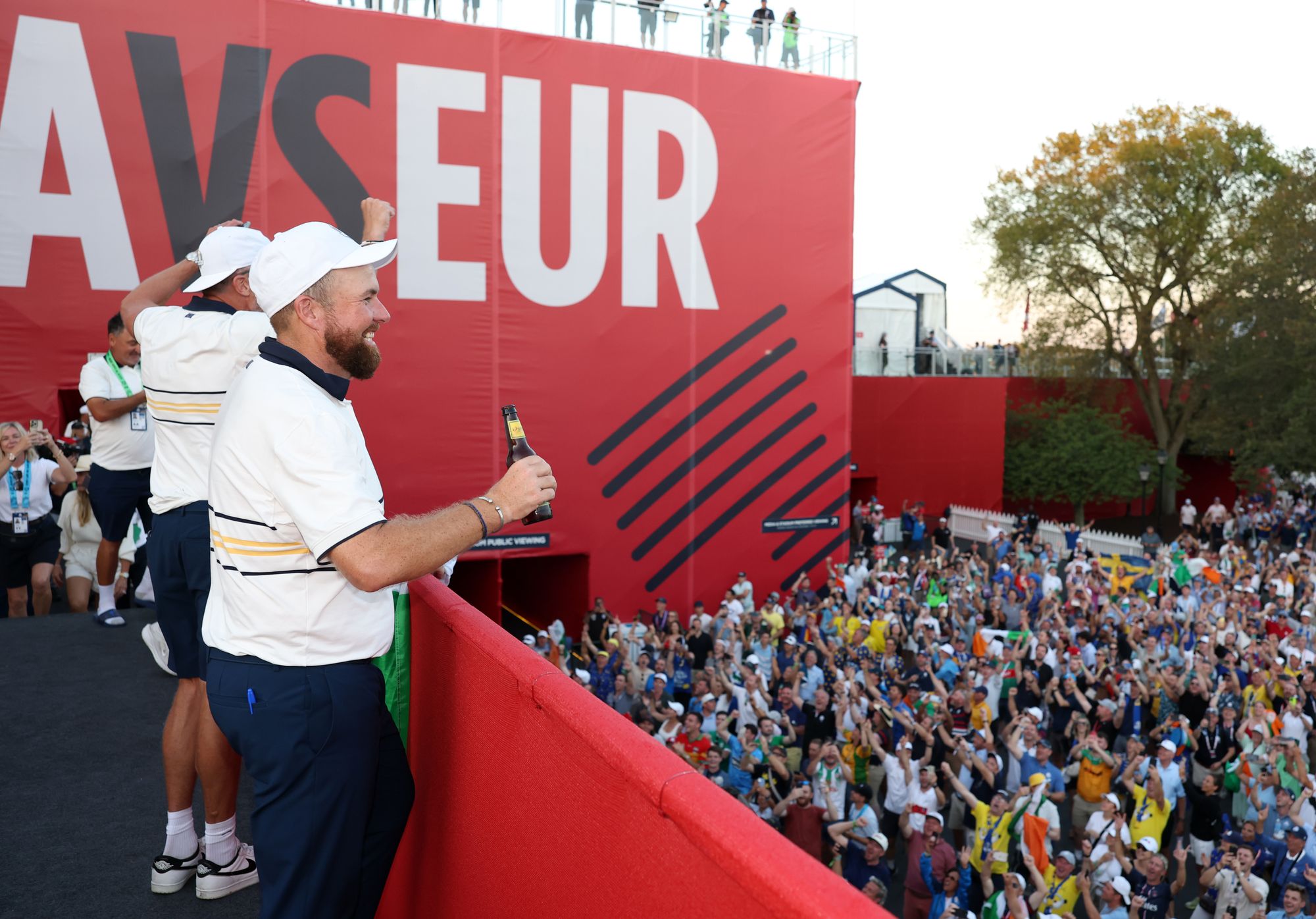 Fans below sing to the players up on the bridge behind the 18th green
