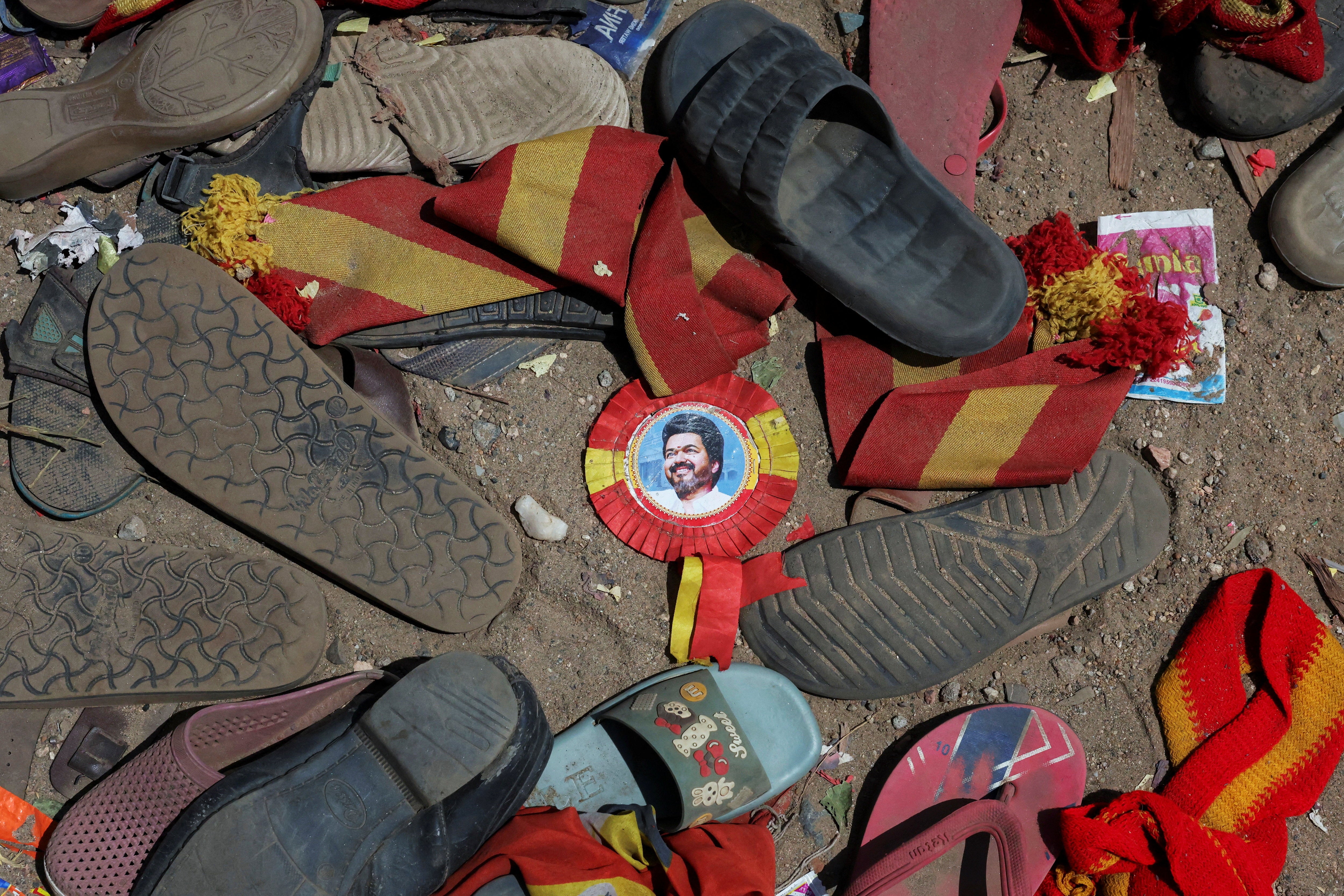 A badge with picture of Vijay lies amid footwear left by attendees at the site of the stampede