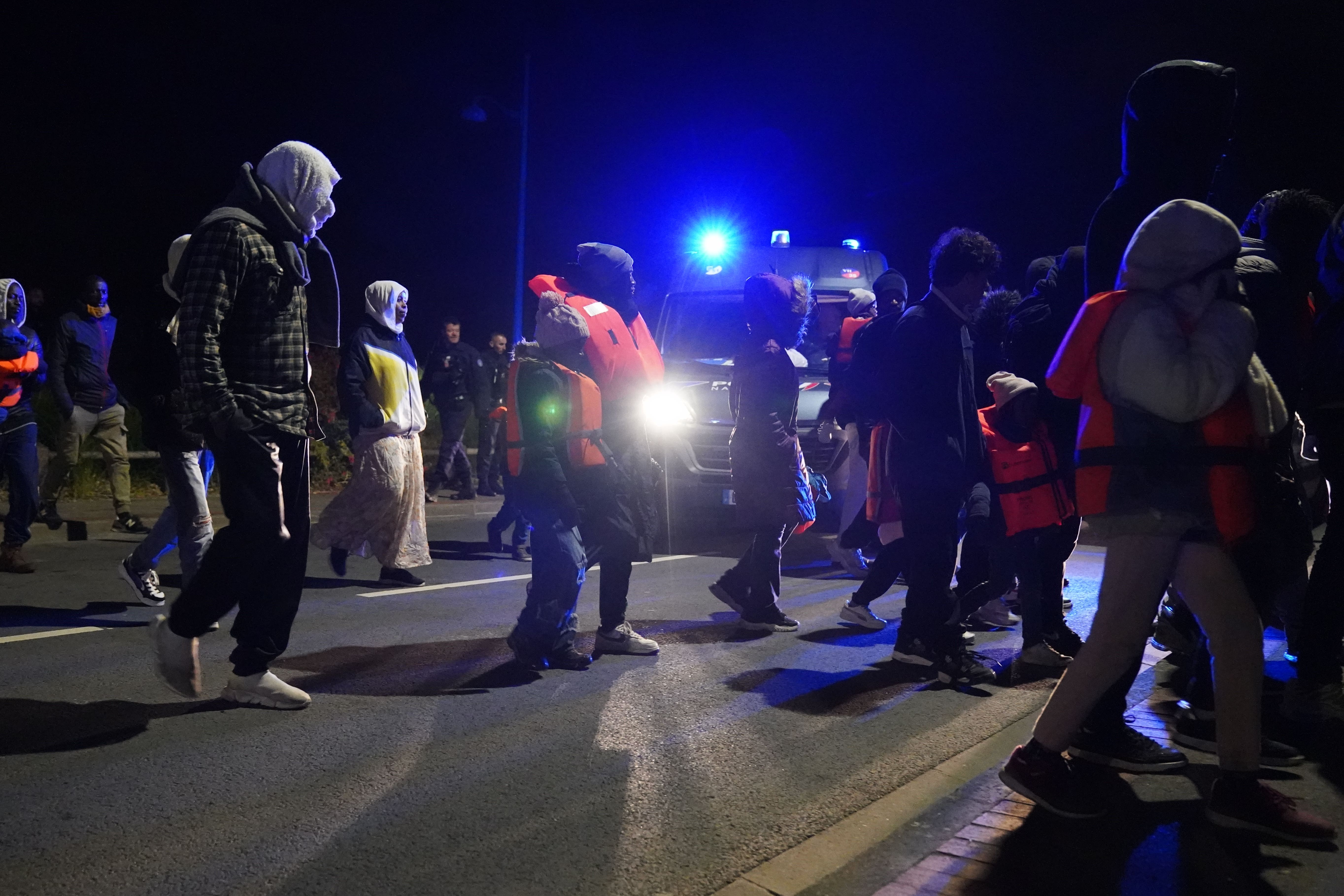 French police officers observe a group of people near a canal in Gravelines, France, where migrants were attempting to board a small boat to cross the Channel (Gareth Fuller/PA)