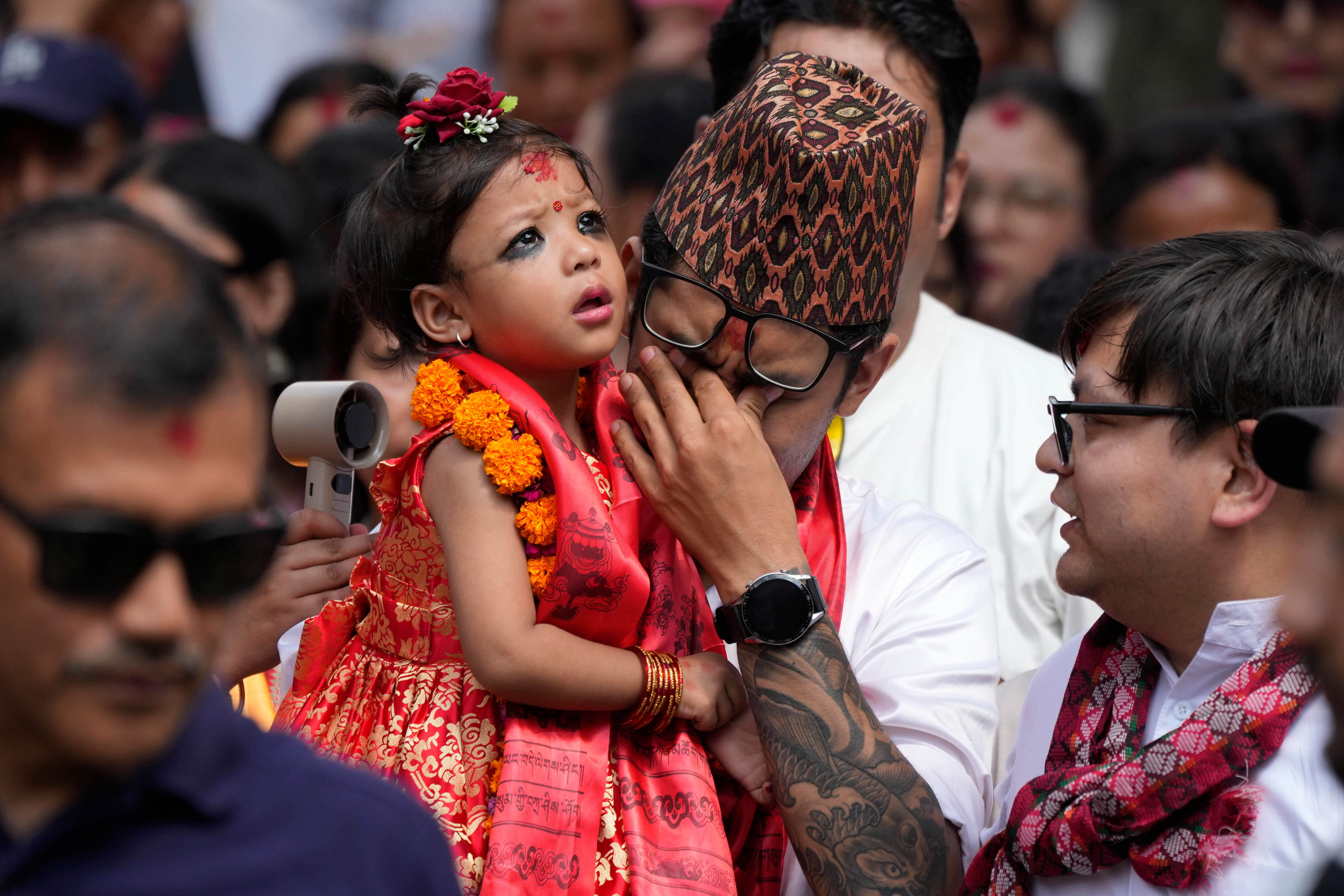 Nepal's newly appointed living goddess, Kumari Aryatara Shakya, is carried by her father as they walk towards Kumari Ghar