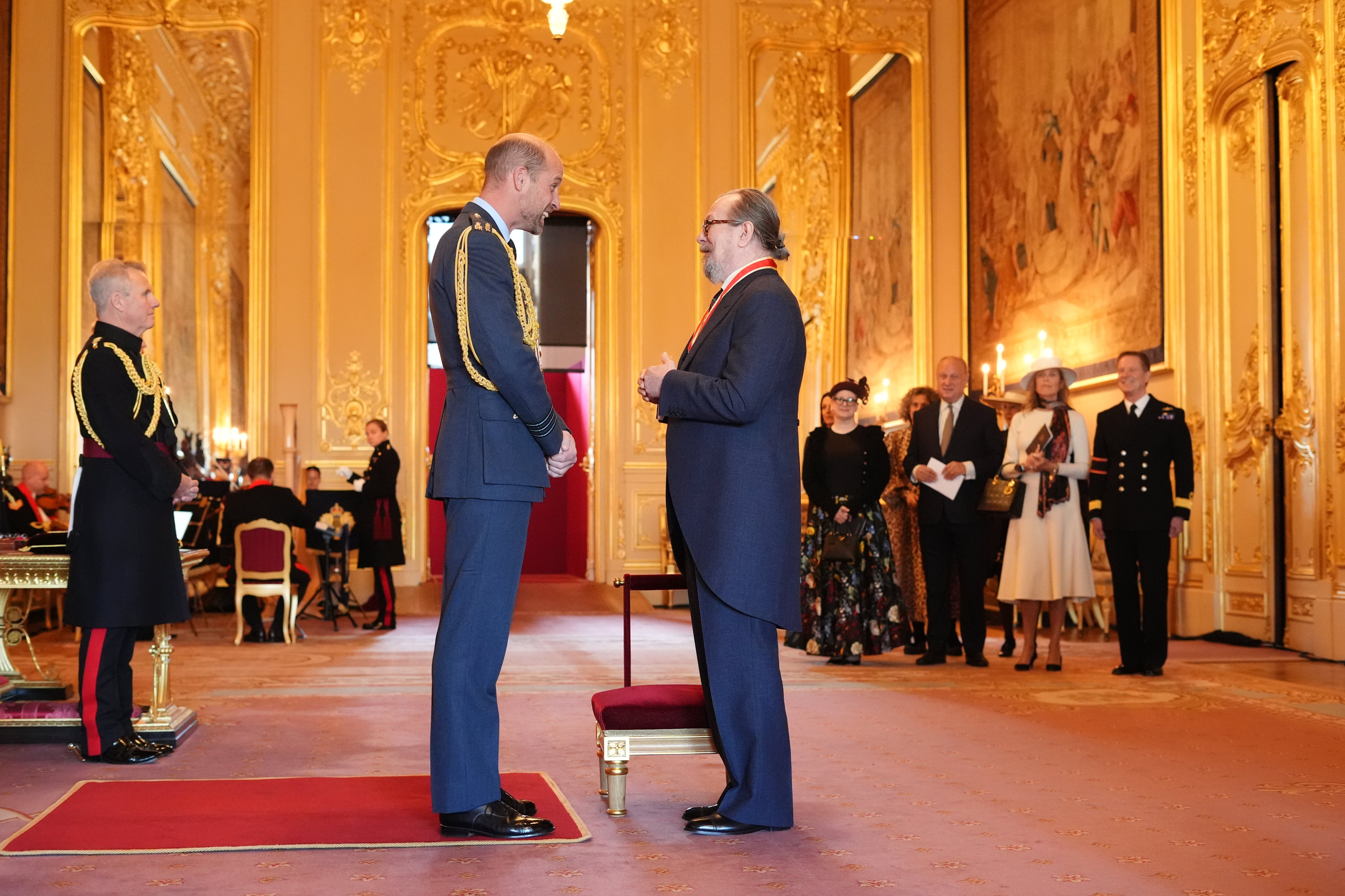 Sir Gary Oldman speaking with Prince William as he receives his honour