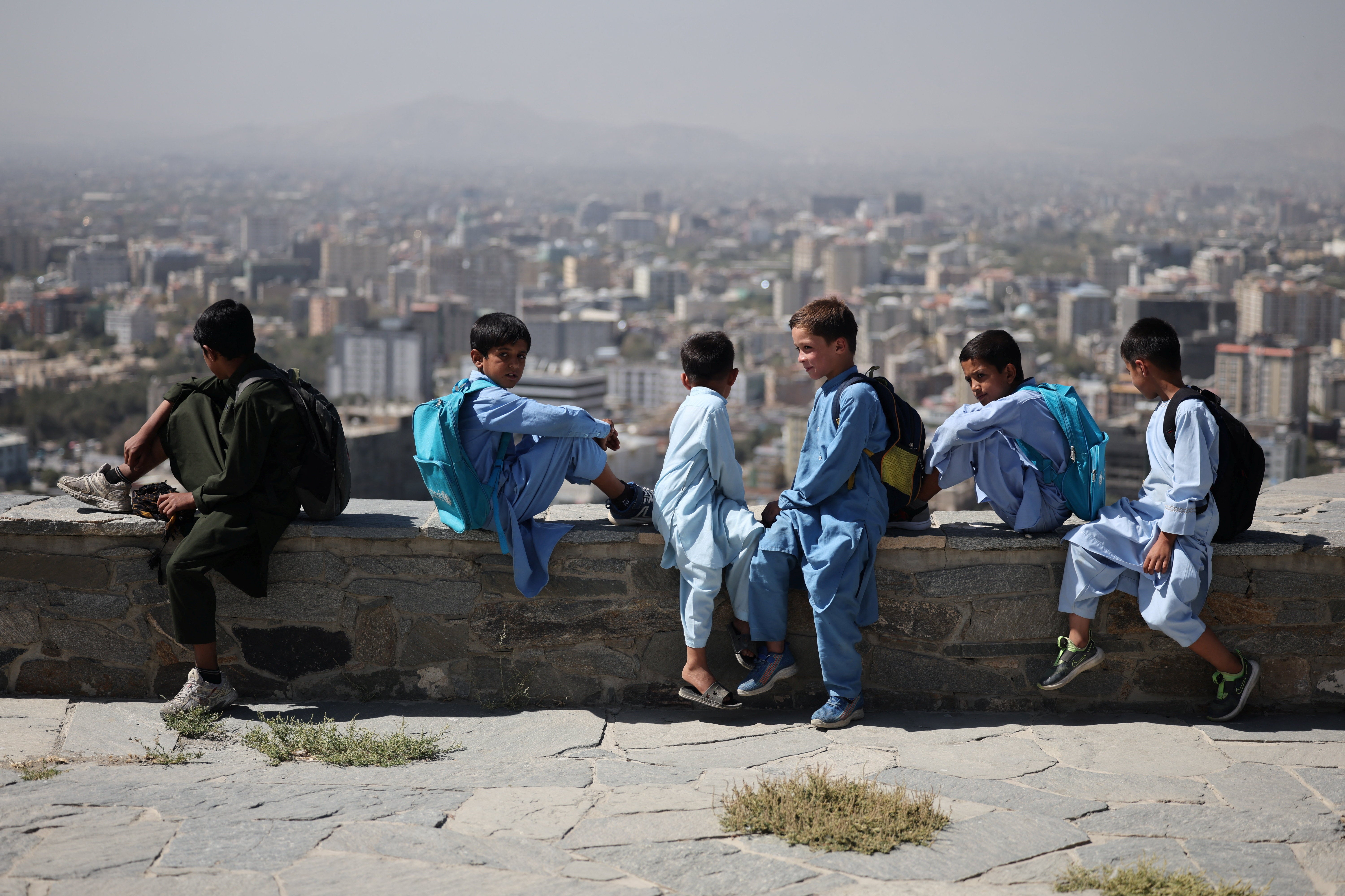 Afghan children sit on a concrete bench at a hilltop, amid telecom shutdown across the country, in Kabul