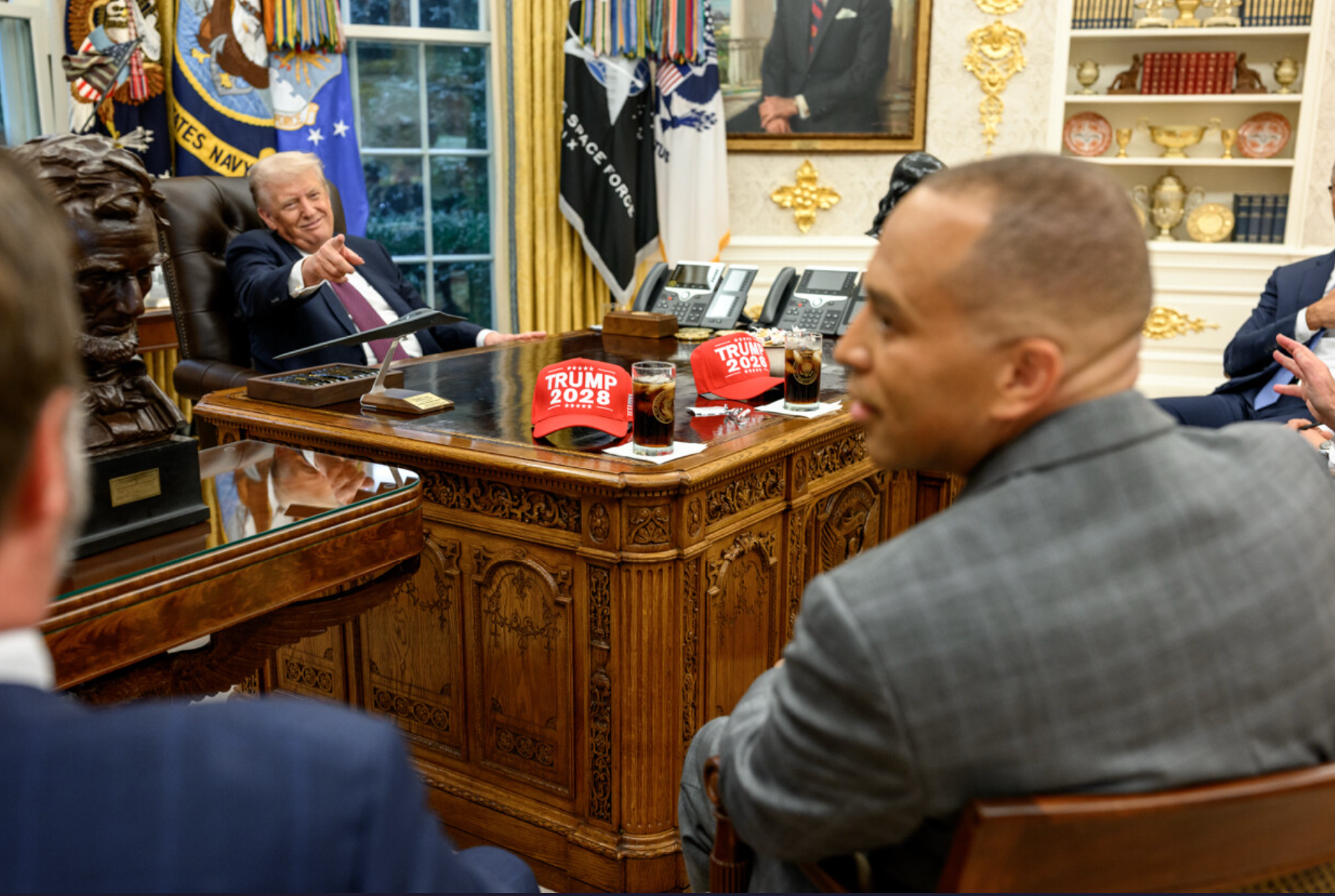Donald Trump points towards Hakeem Jeffries during talks in the Oval Office aimed at avoiding a government shutdown as two 'Trump 2028' hats sit on his desk