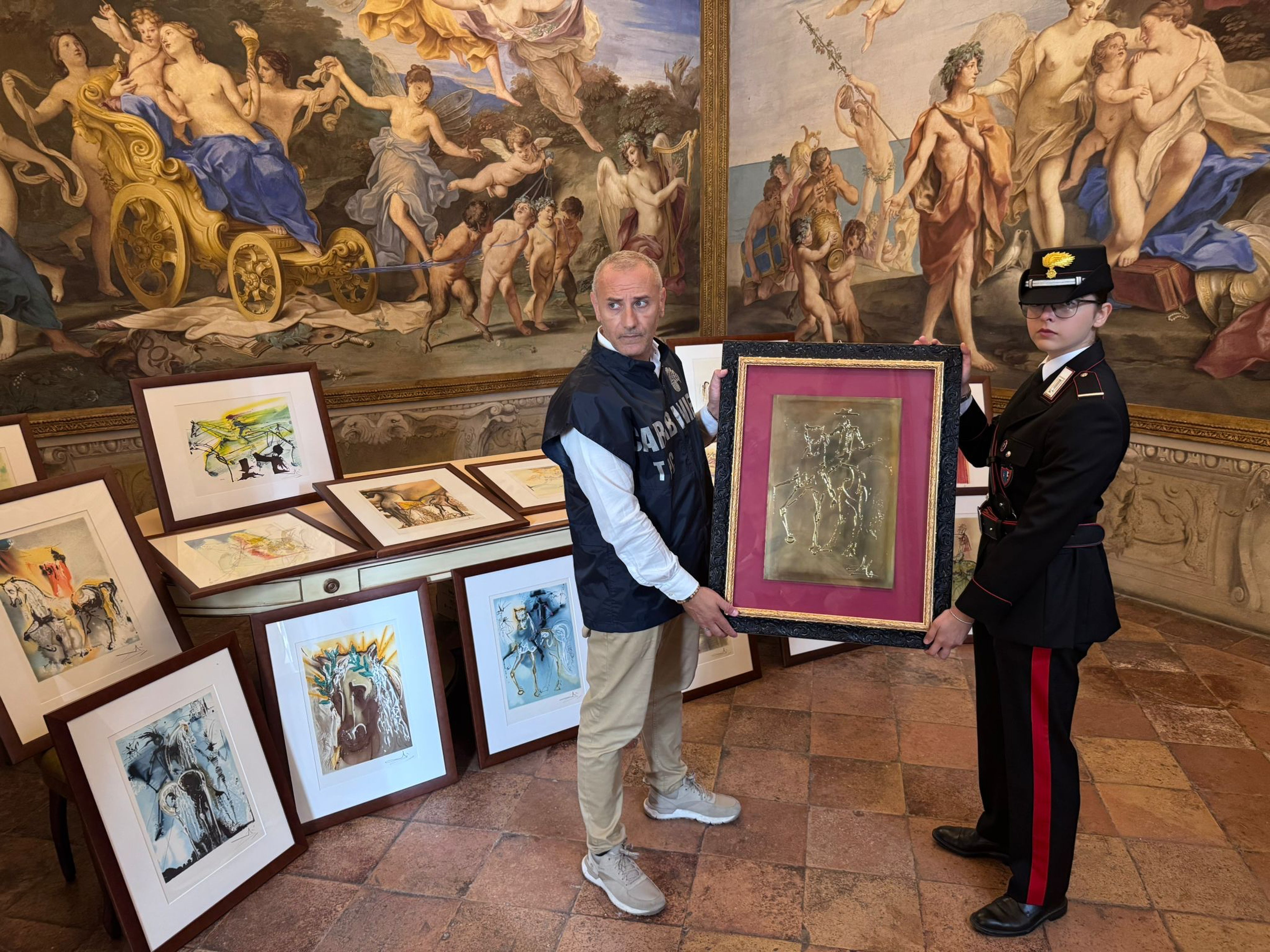 Two officers pose with some of the 21 artworks that were seized on suspicion of being fakes