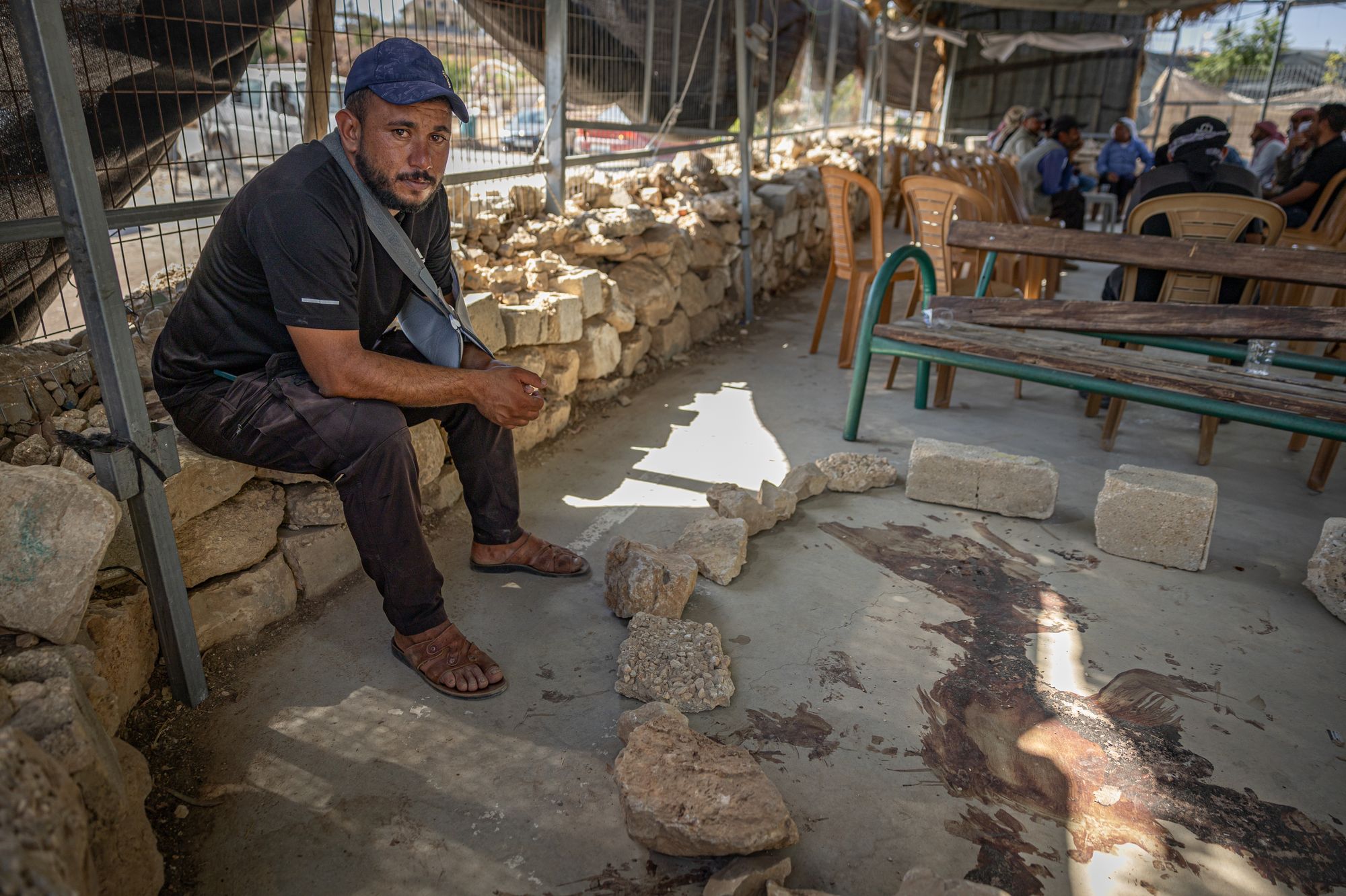 Awdah’s cousin Ahmed, injured from the attack, sits next to the dried pool of blood where his relative was shot dead by settlers in the West Bank