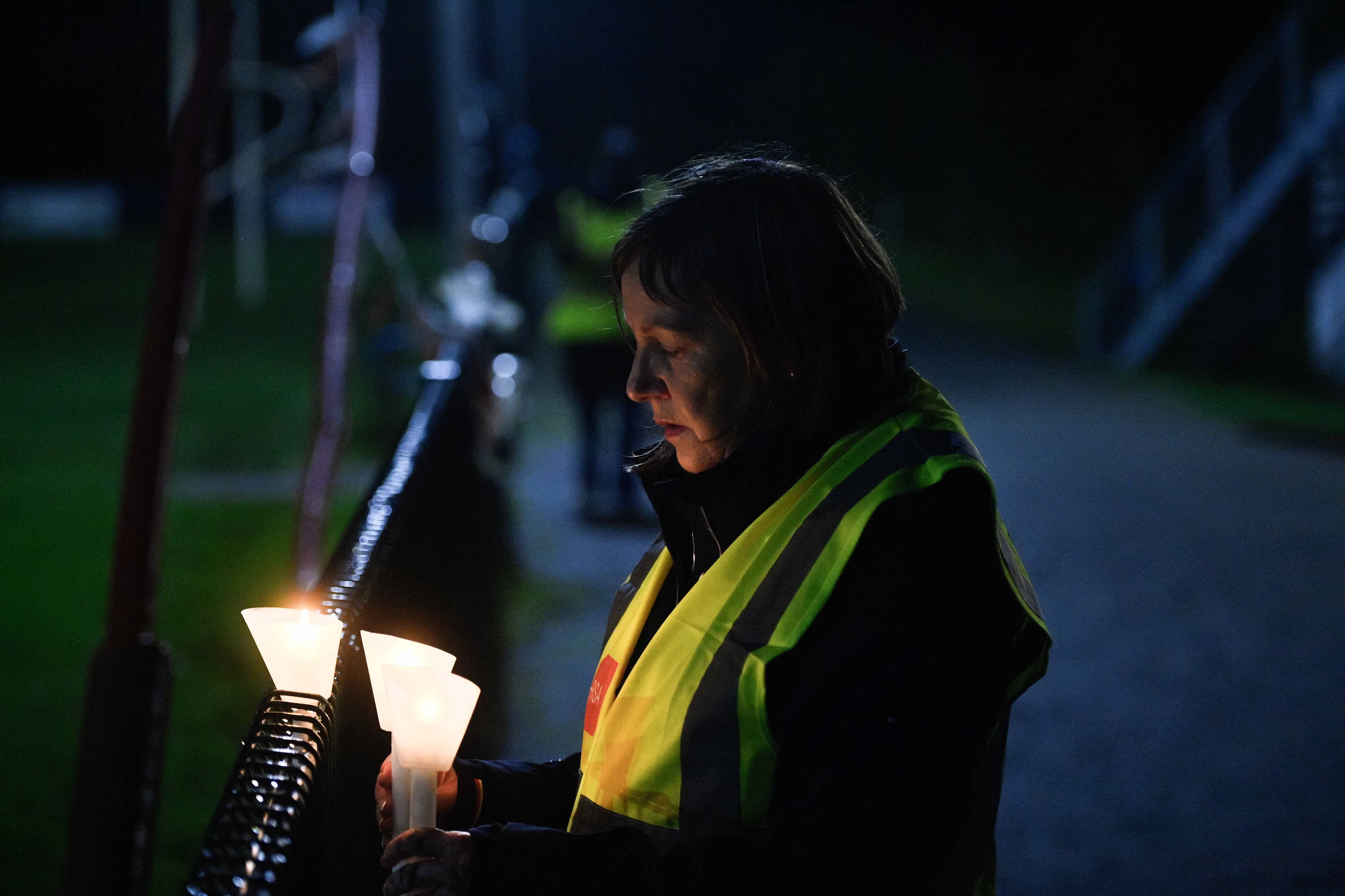A person lighting a candle during a vigil in Louth for Mark and Louise O’Connor and their son Evan, whose bodies were found at the family’s home in Drumgowna (Mark Marlow/PA)