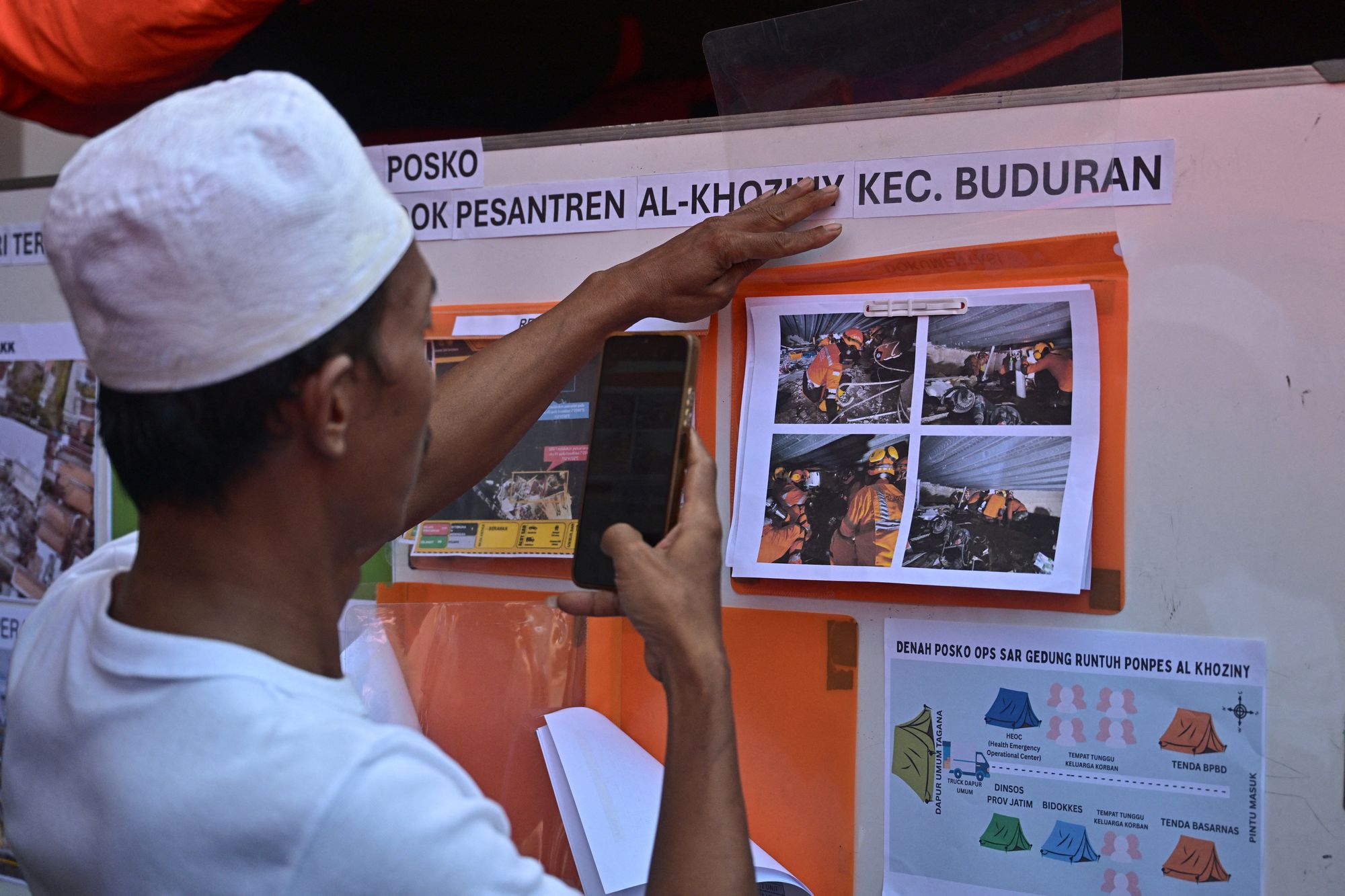 A relative looks at pictures on a notice board as search and rescue work continues at Al Khoziny Islamic Boarding School in Sidoarjo