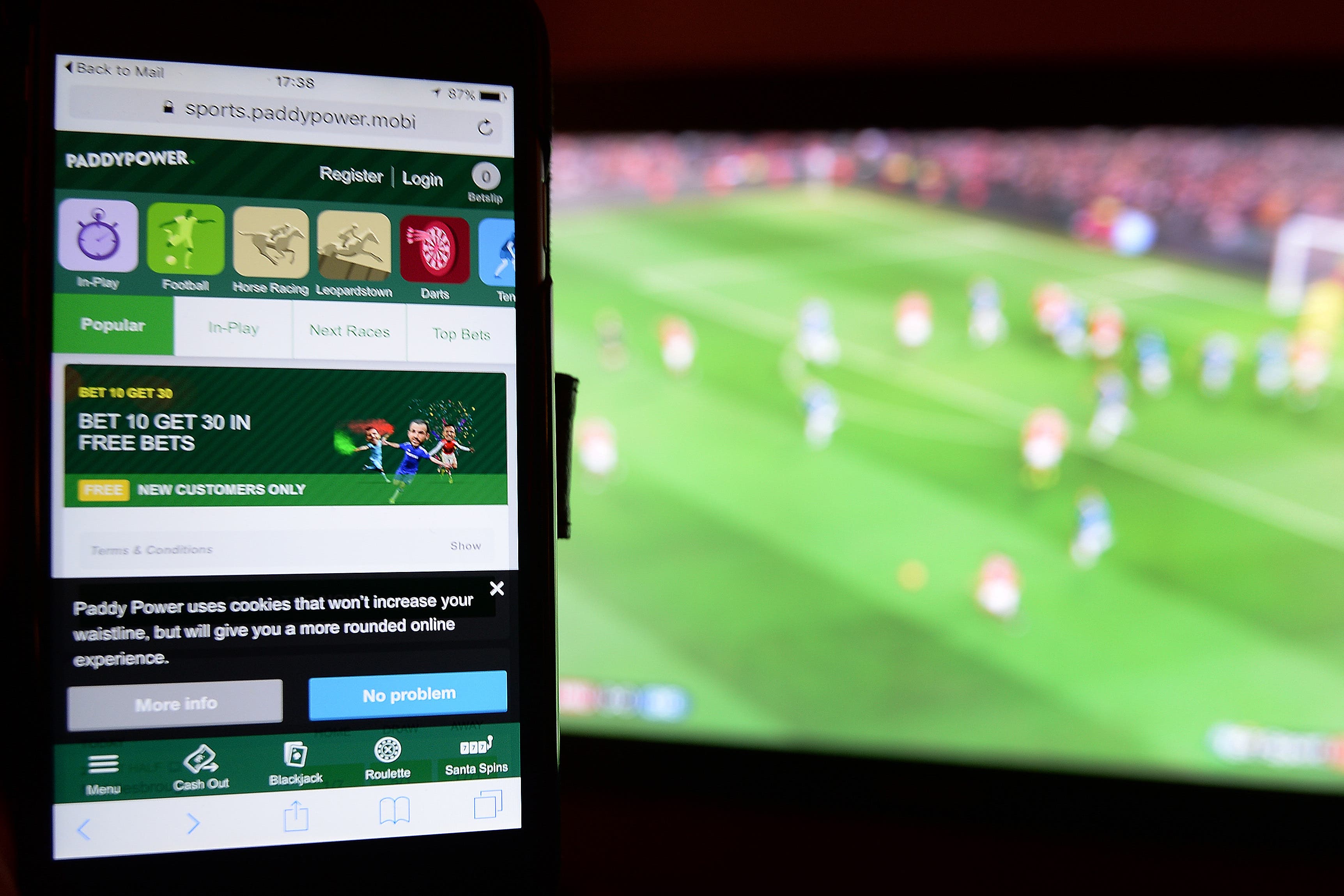 A smartphone user accesses the Paddy Power gambling website while watching a football match on television.