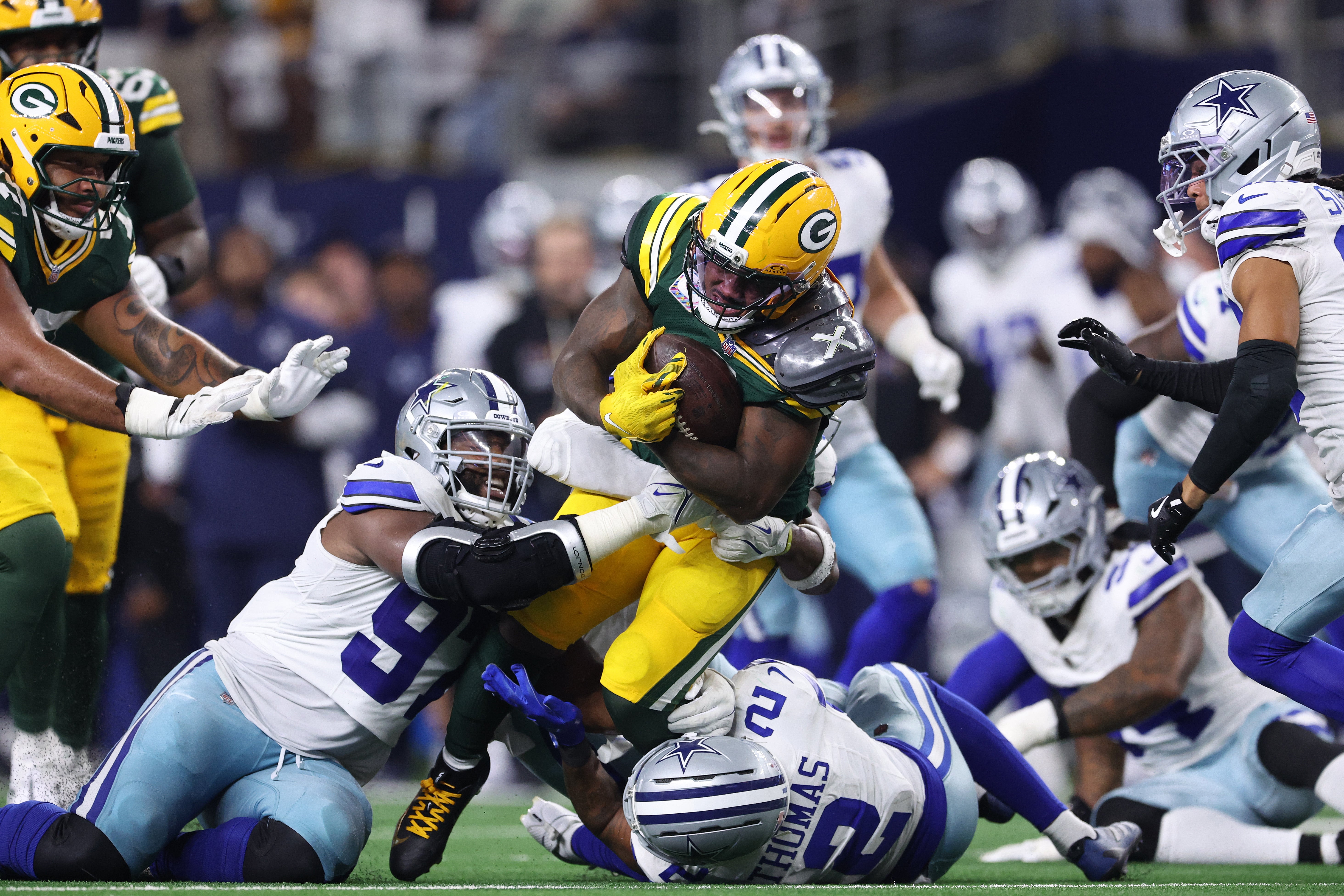 Green Bay Packers ‘Josh Jacobs is tackled by Osa Odighizuwa and Juanyeh Thomas of the Dallas Cowboys during overtime on Sunday