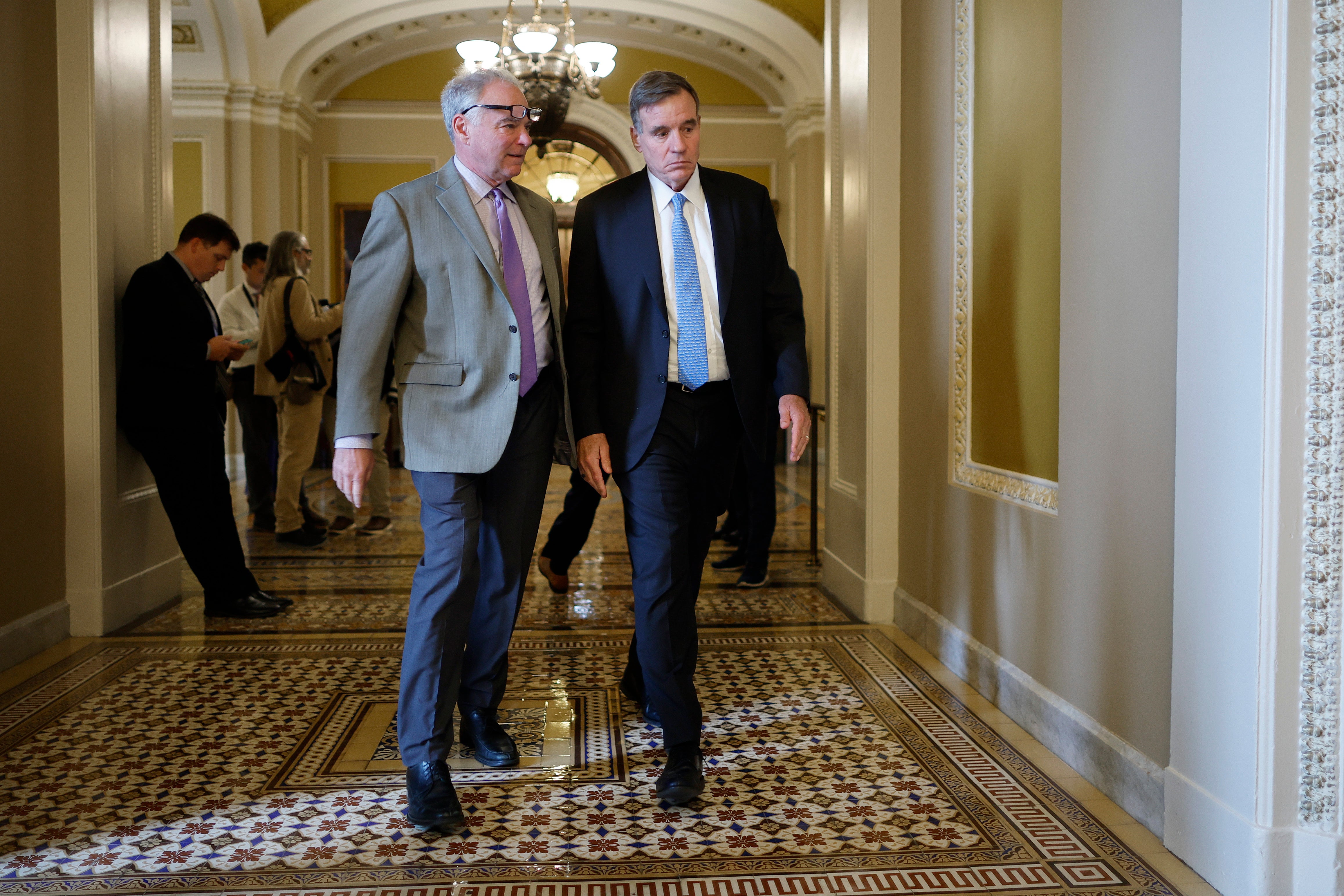 Sen. Tim Kaine (D-VA) (L) and Sen. Mark Warner (D-VA) represent hundreds of thousands of federal workers who have been affected by DOGE but who could lose their paychecks during a shutdown.