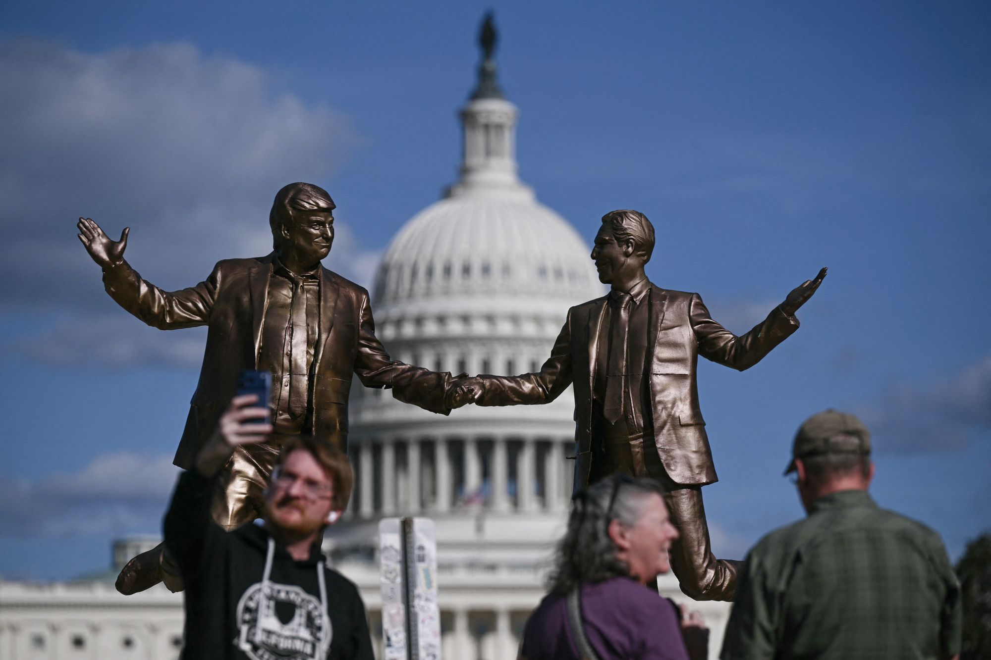 People pose for photos near the Epstein-Trump statue on Thursday