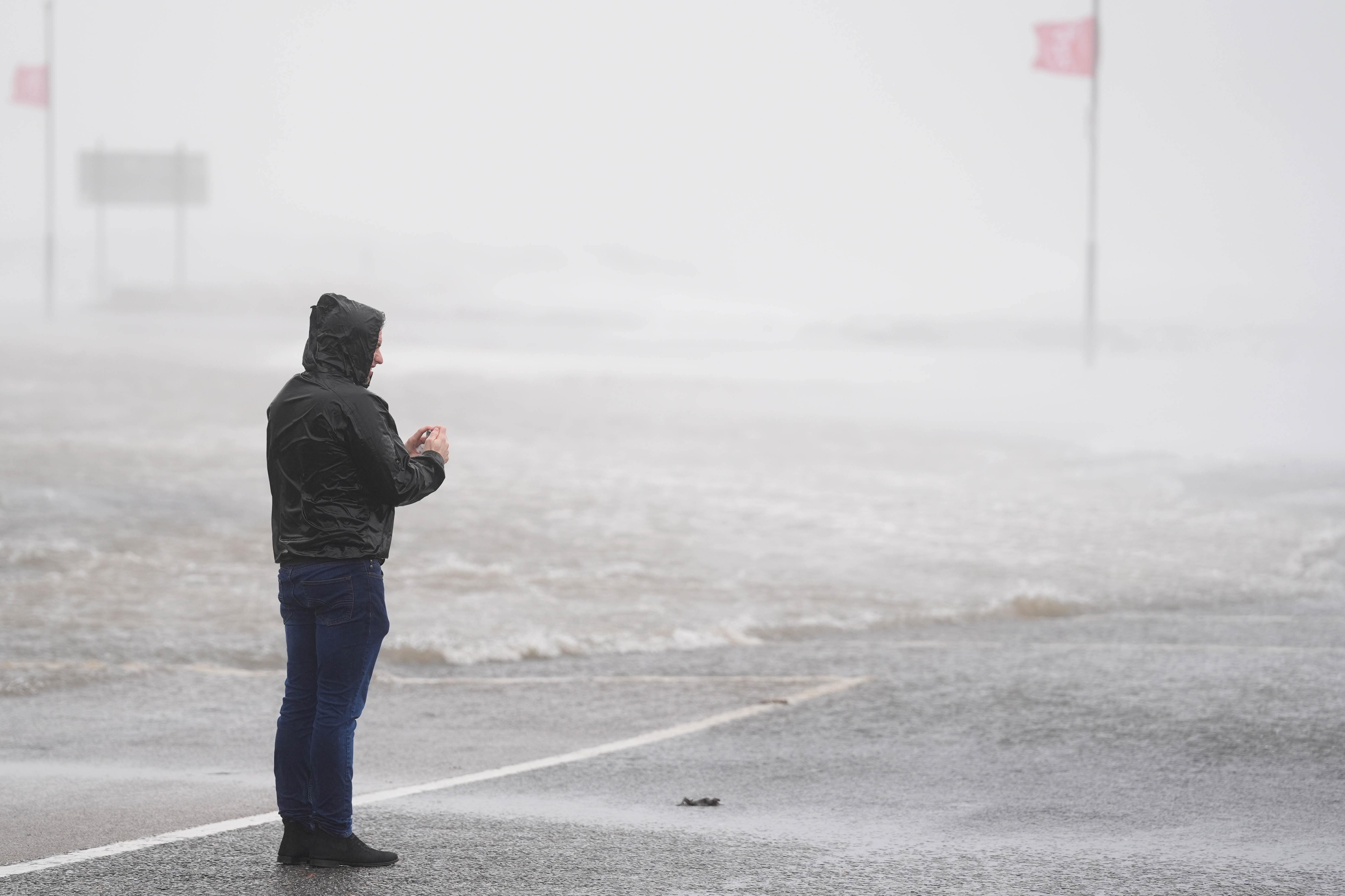 A person looks at a flooded road (Brian Lawless/PA)