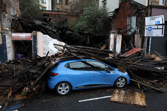 <p>Debris from a collapsed building falls on a car in Broomielaw in Scotland, with the country seeing the worst of the weather</p>