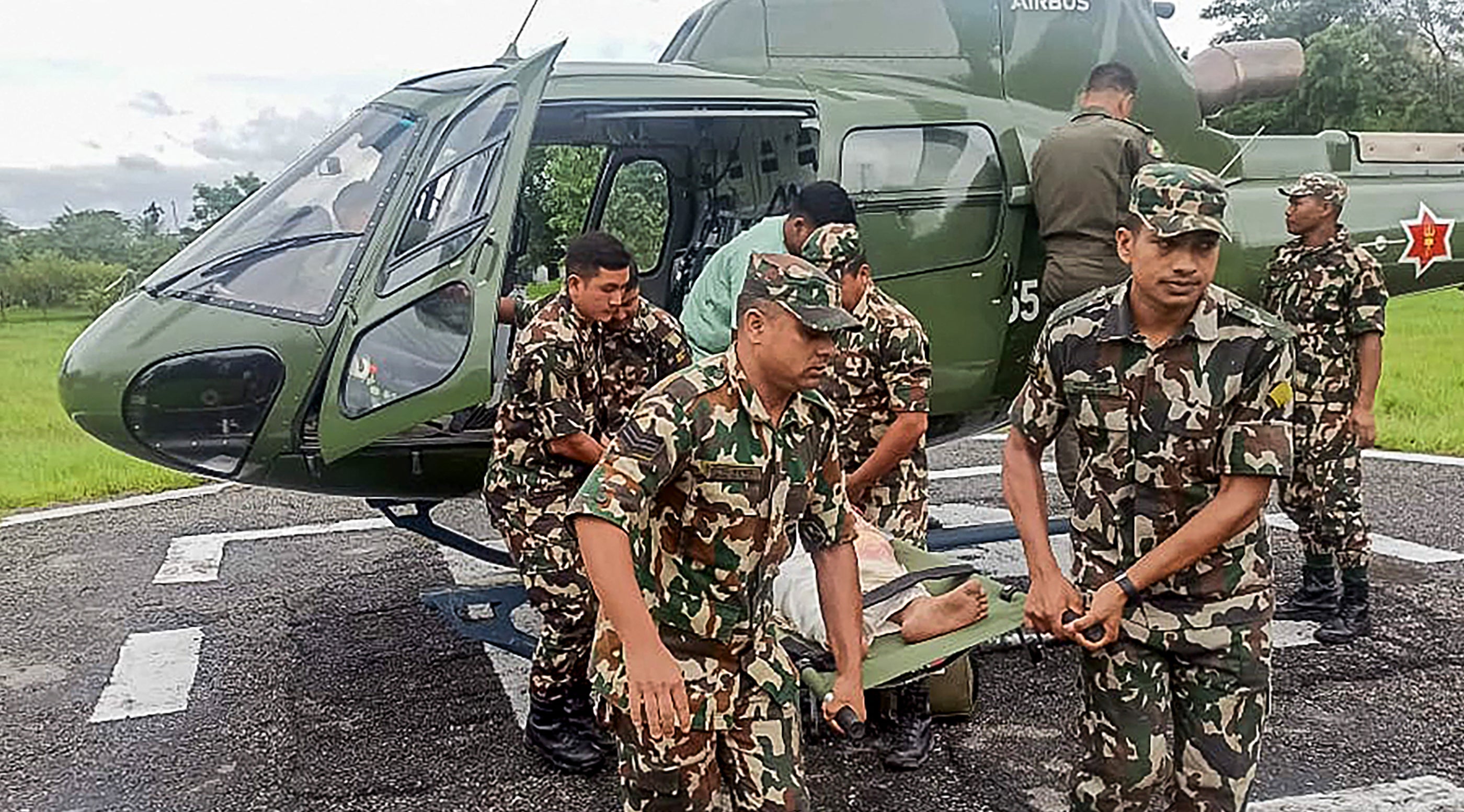 Army personnel carrying a landslide victim evacuated by a helicoper following heavy rain-triggered landslides and floods in Nepal