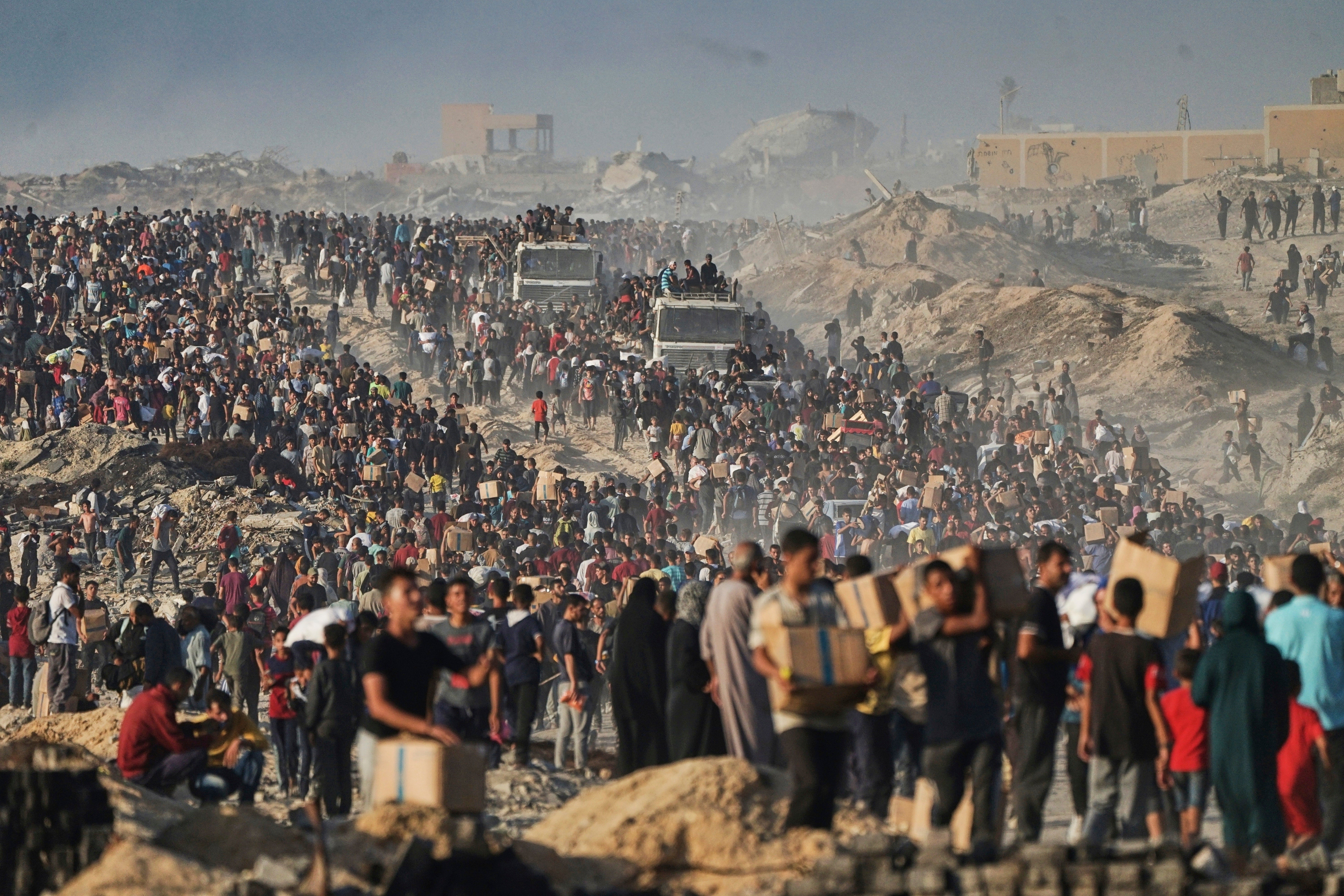 FILE PHOTO: People carry humanitarian aid unloaded from a World Food Program convoy in Gaza on June 16. The WHO said in August that more than half a million people in Gaza are “trapped in famine”