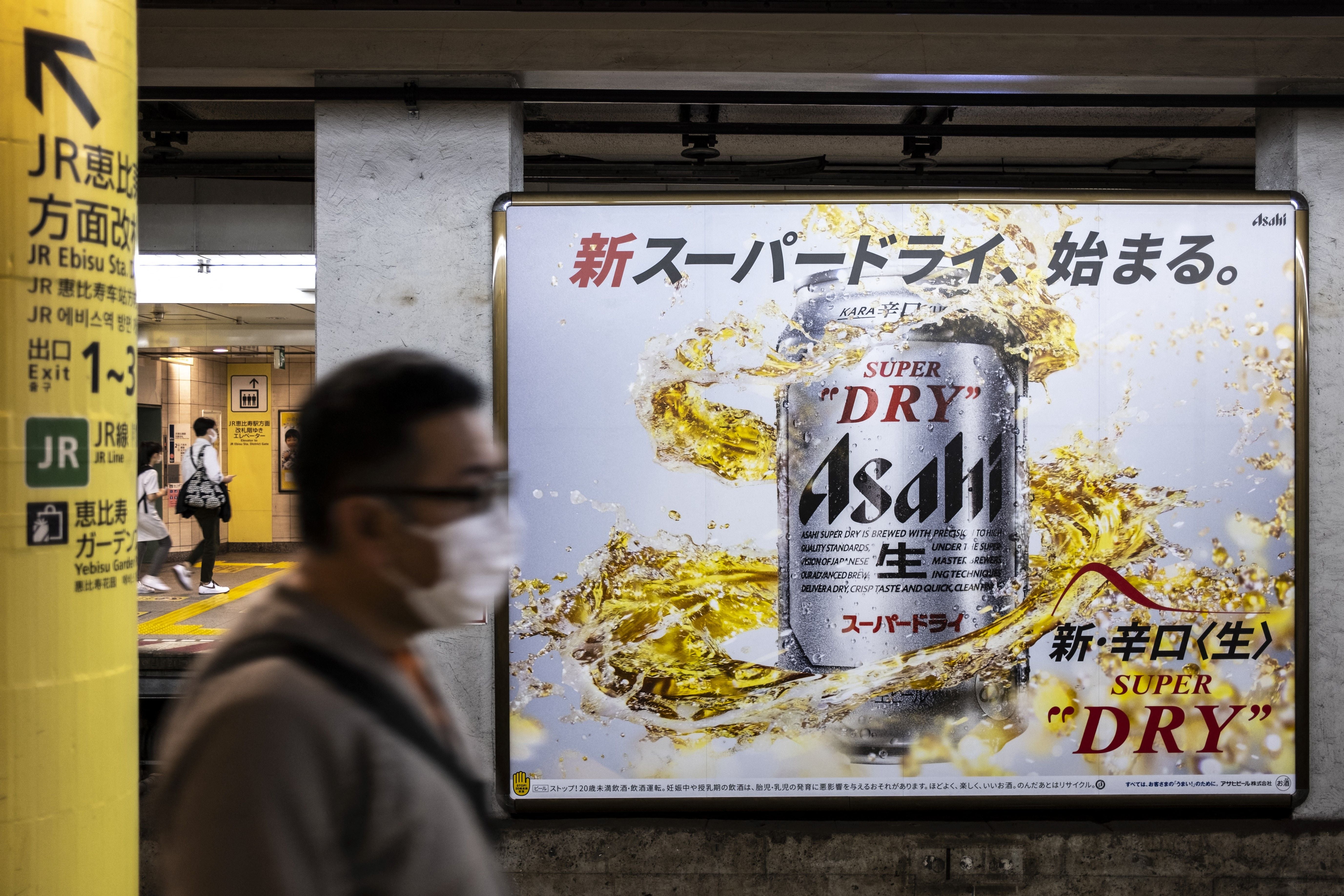 <p>File photo. A man walks past an "Asahi" beer advertising in a train station in Tokyo </p>