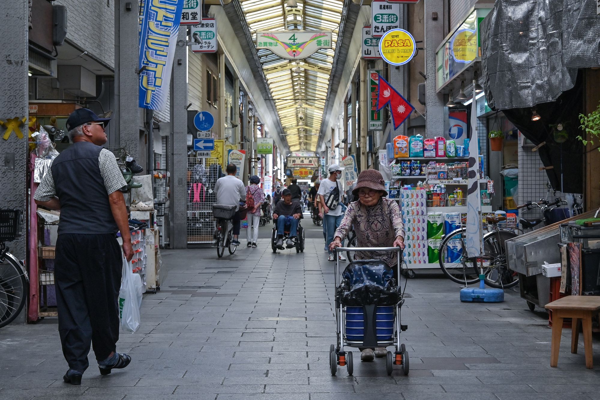 <p>This photo taken on 1 October 2025 shows shoppers walking through the Tsurumibashi ‘shotengai’, an old covered shopping street in the Nishinari ward of Osaka</p>