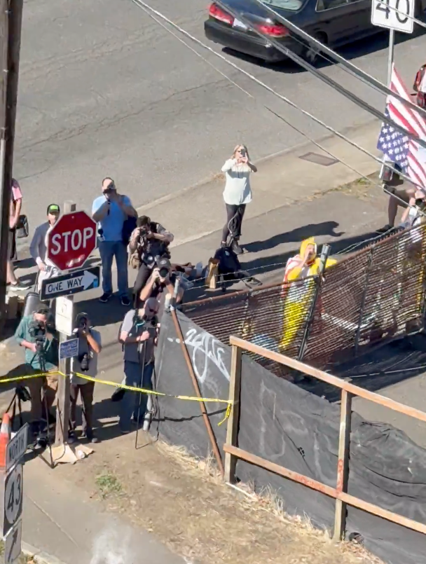 Noem's trip to stare down the Antifa 'army'revealed a woman taking a photo with her cell phone and a man in a chicken costume