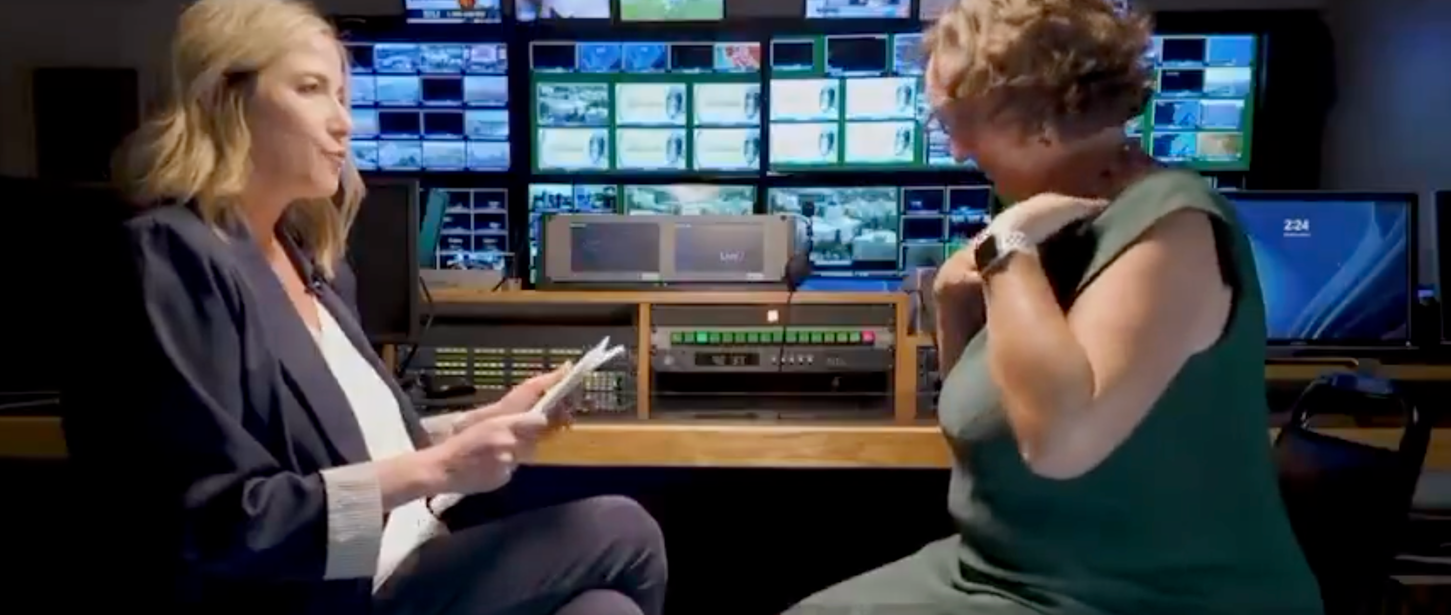 California gubernatorial candidate Katie Porter attempts to take off her lapel mic after being angered by CBS reporter Julie Watts's questions