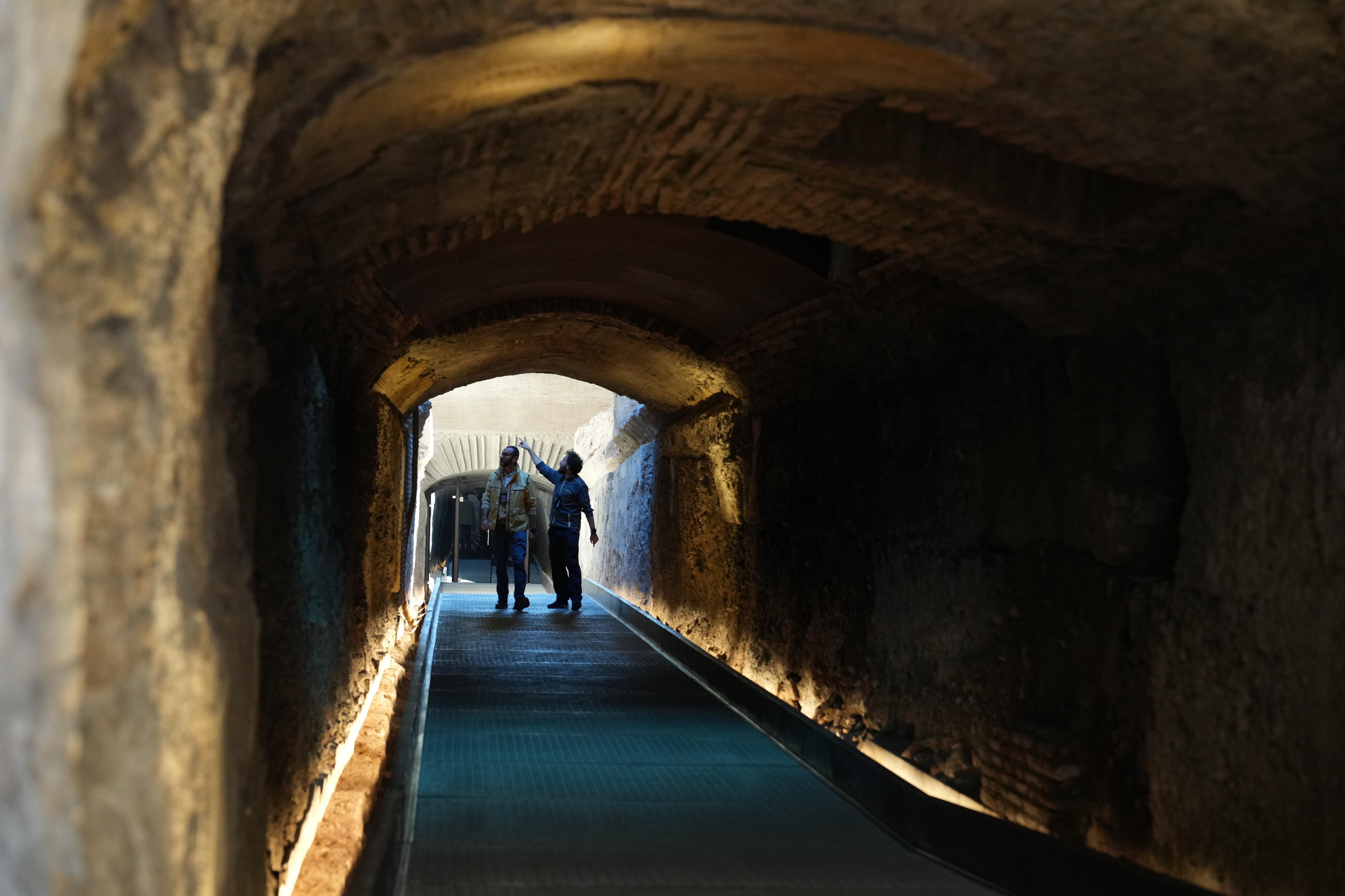 Workers walk in the so-called 'Passage of Emperor Commodus', a newly restored tunnel ancient Roman emperors would use to enter the Colosseum unseen and protected, that will open to visitors at the end of the month