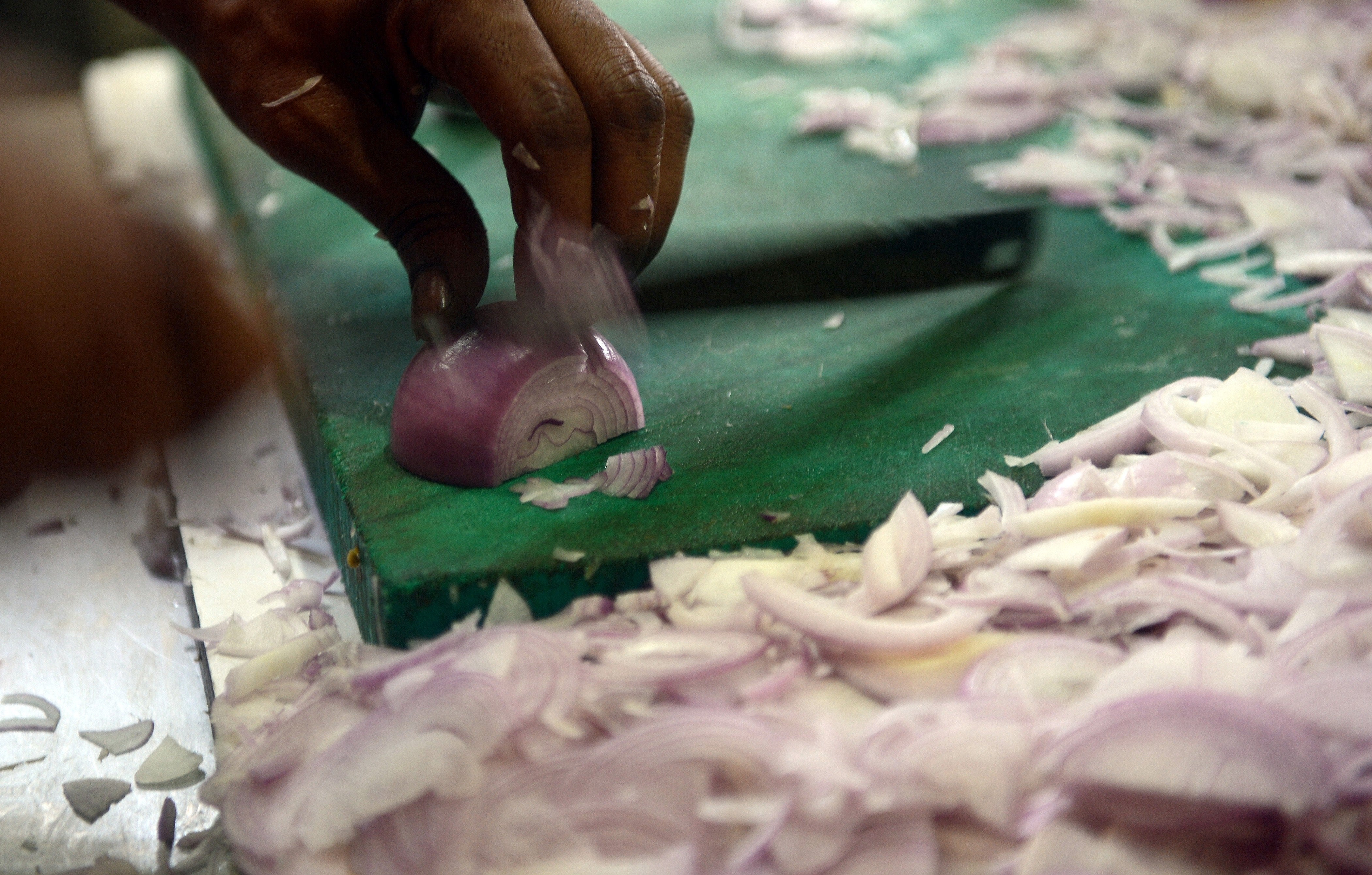 Indian cook chopping onions in the kitchen