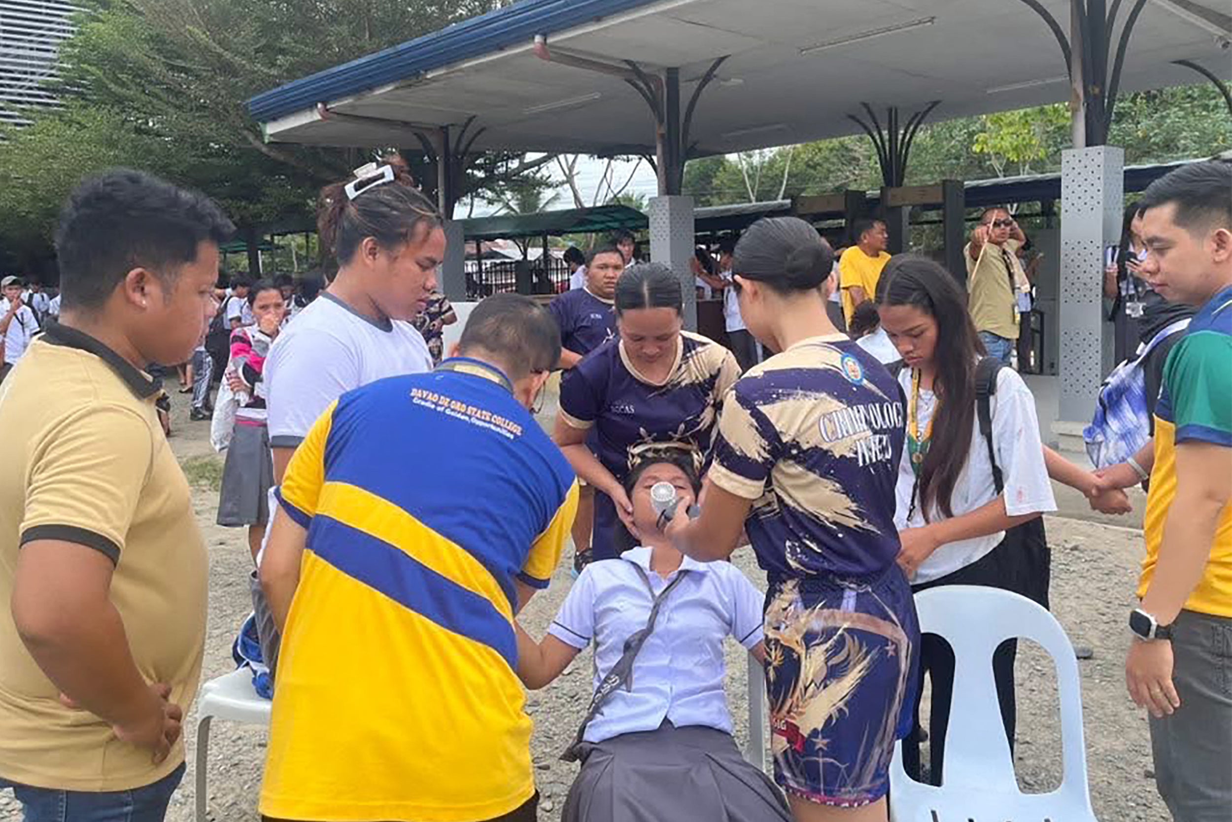 Students helping a fellow student as they gather outside the school buildings after an earthquake in Davao de Oro, Mindanao