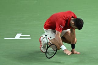 Srbský Novak Djokovic padá na soud během semifinále singlů mužů proti Monackému Valentinu Vacherot