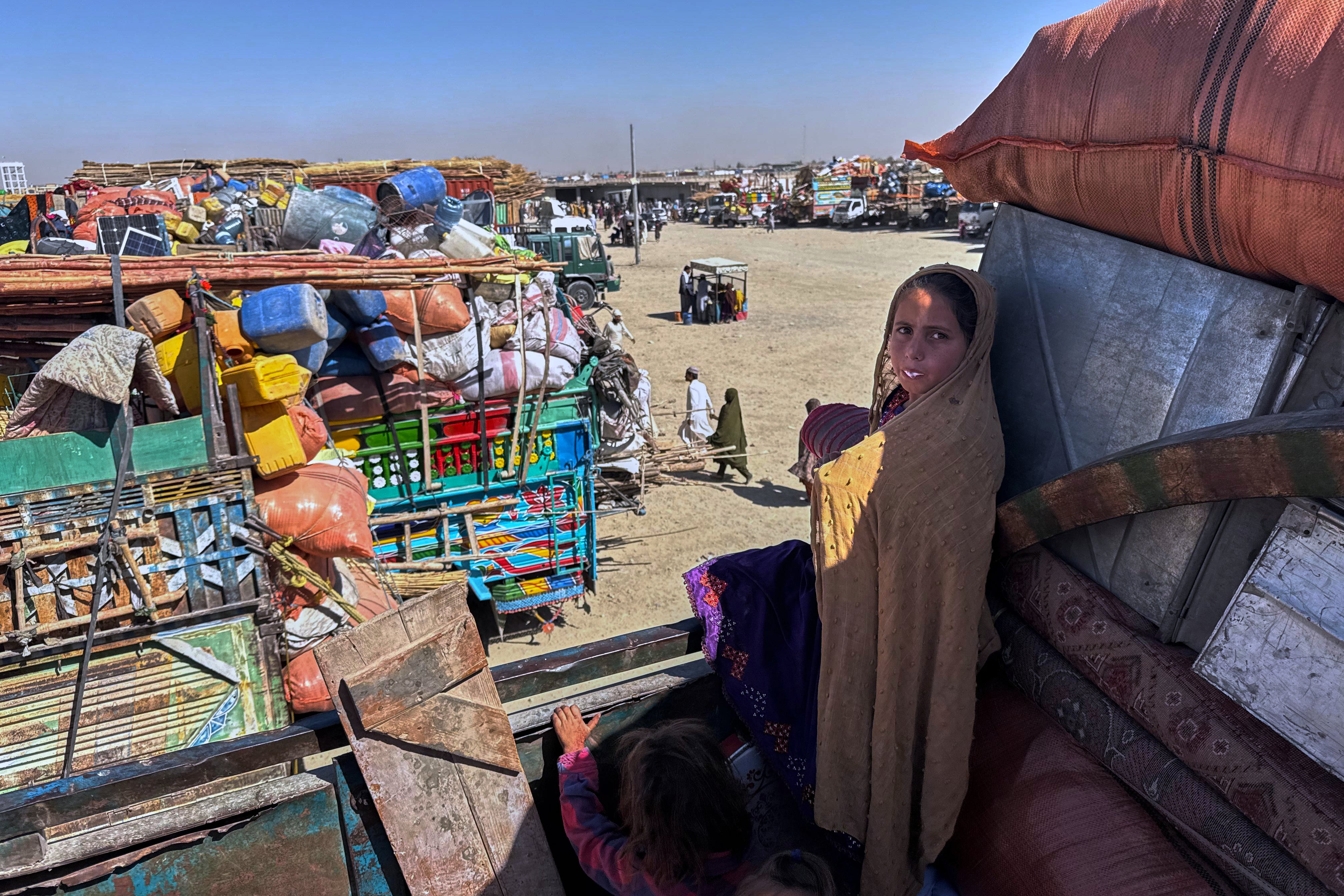 <p>Afghan refugees girls sit over a truck loaded with their belongings last month</p>