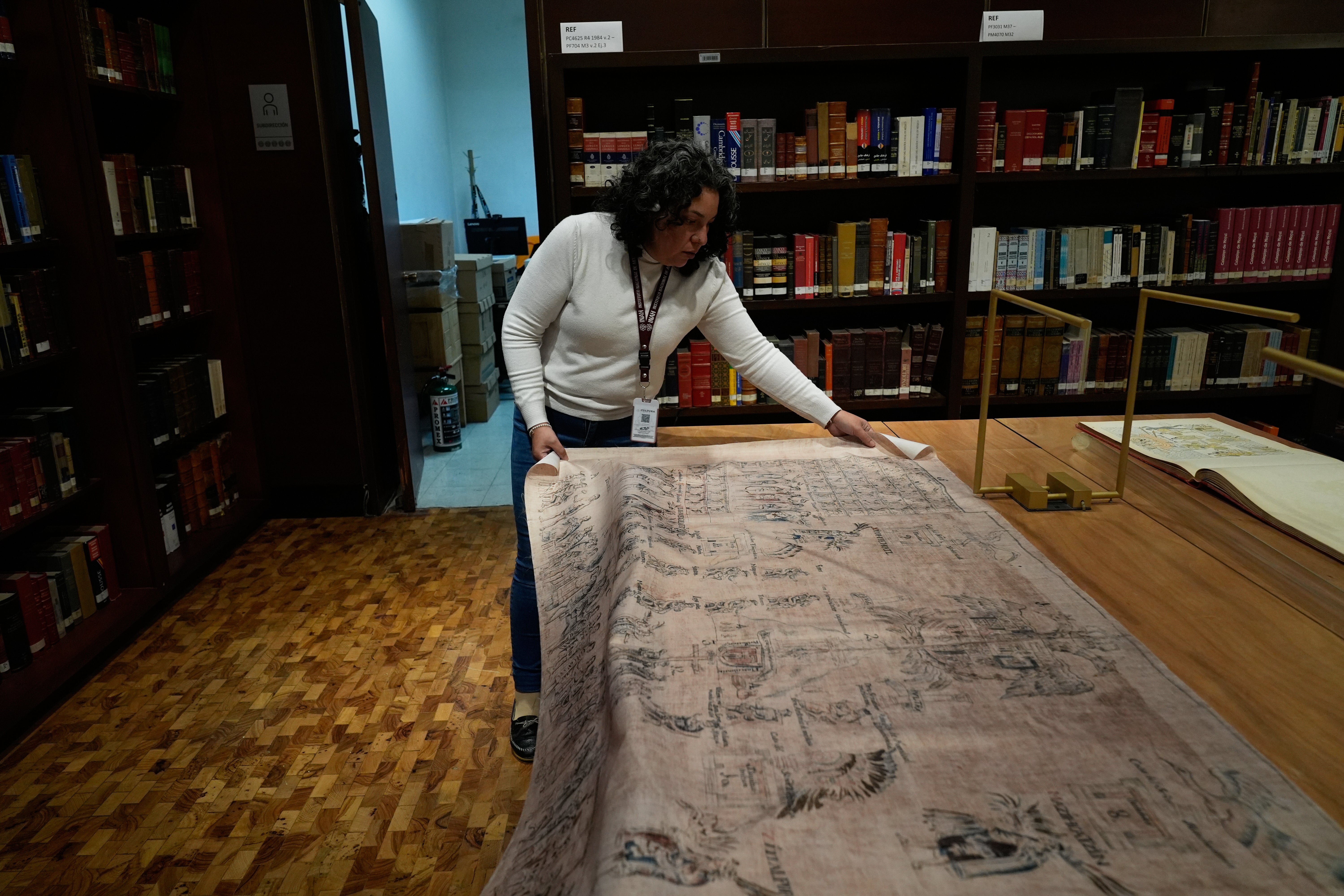 Areli Ortiz, technical deputy director of the National Institute of Anthropology and History, shows a fabric featuring images of La Malinche and Hernan Cortes from a facsimile of part of the 16th century Tlaxcala Codex in Mexico City